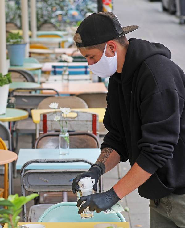 Ein Kellner räumt vor dem Kölner Lokal Herr Pimock einen Tisch ab.