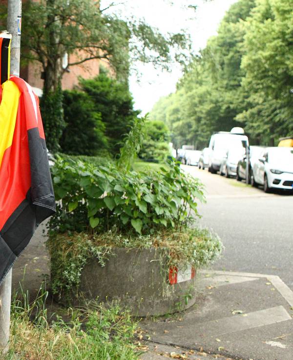 Plastik-Klatschstangen in den Farben von Deutschland sowie eine Deutschland-Fahne in einem Mülleimer.