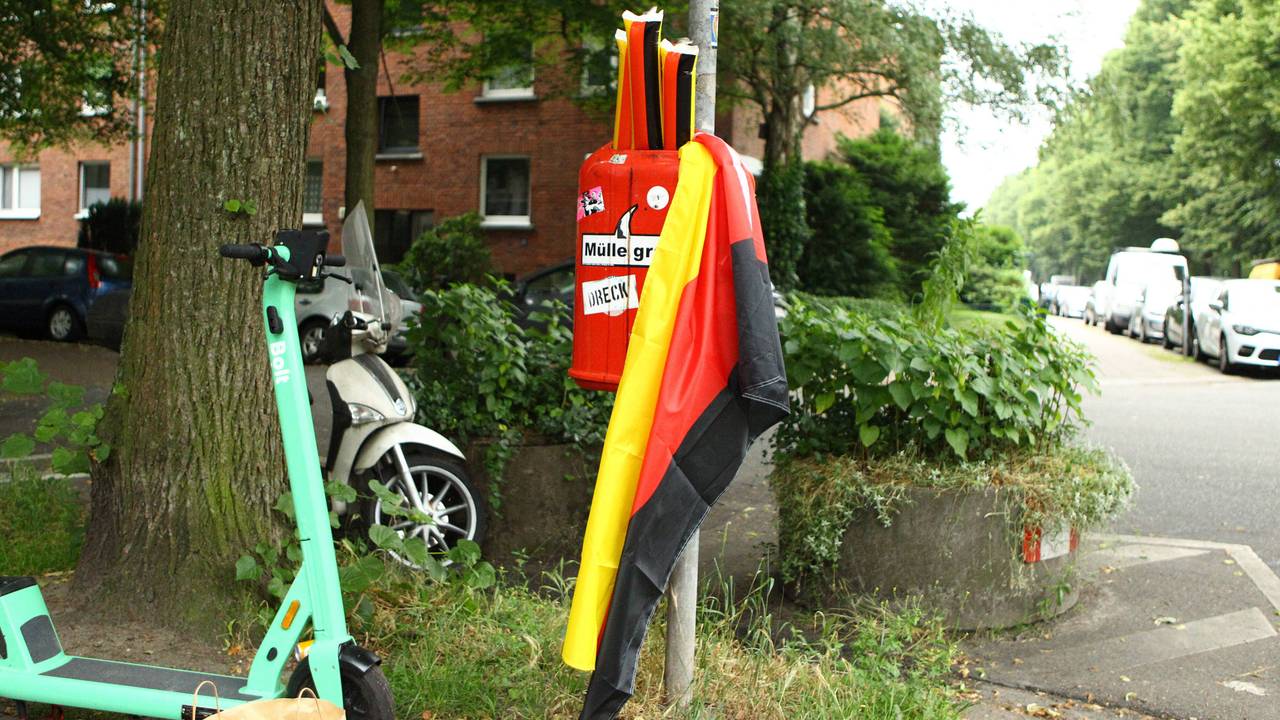 Plastik-Klatschstangen in den Farben von Deutschland sowie eine Deutschland-Fahne in einem Mülleimer.