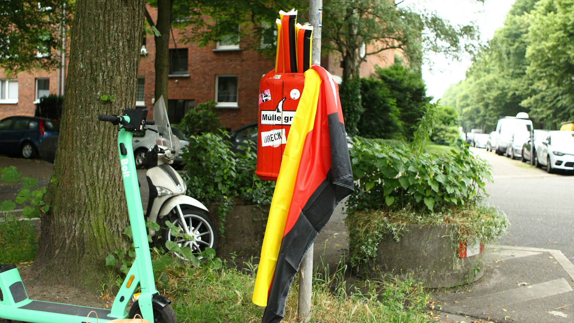 Plastik-Klatschstangen in den Farben von Deutschland sowie eine Deutschland-Fahne in einem Mülleimer.