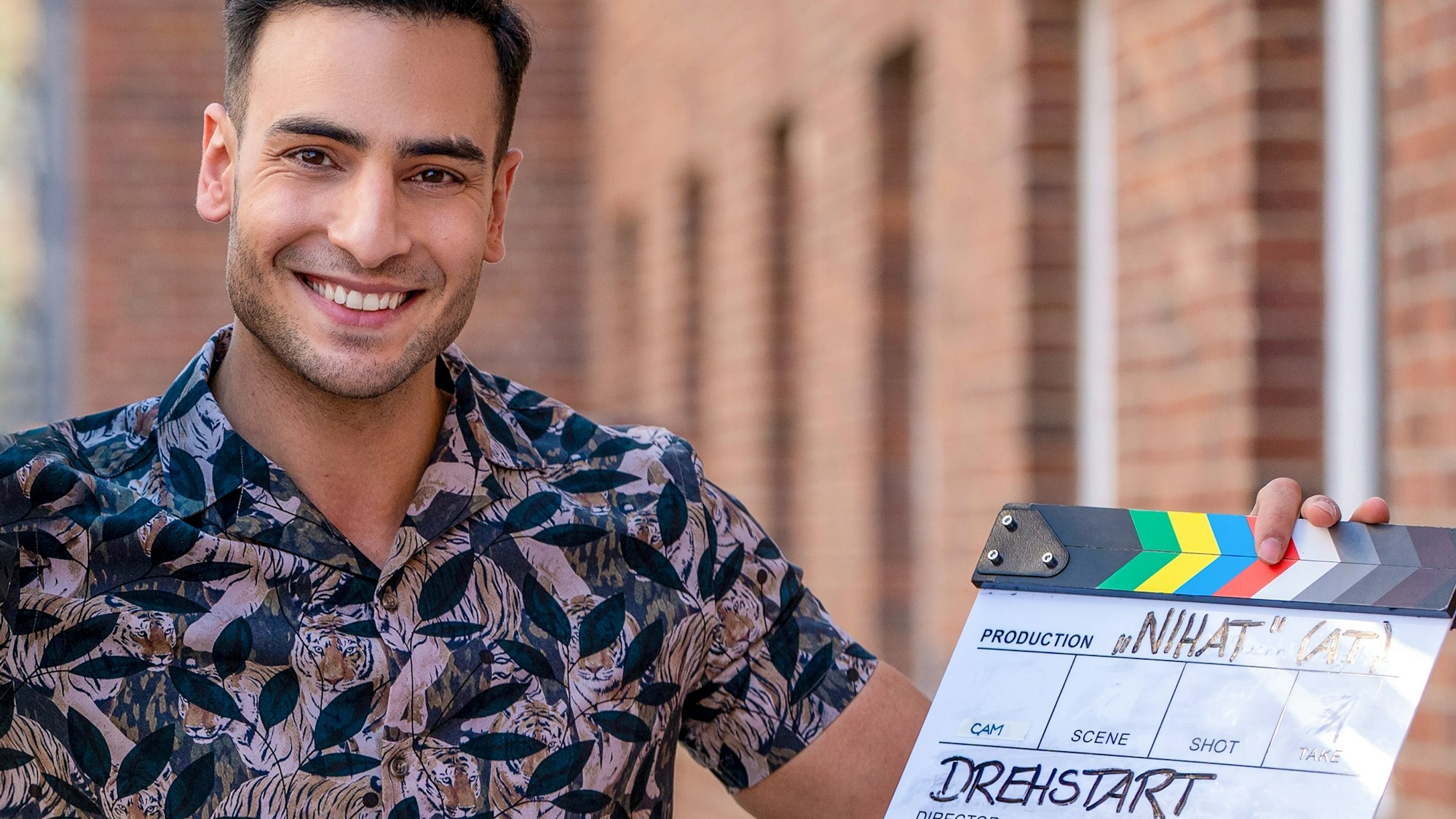 Timur Ülker zeigt stolz die Klappe zum Start von „Nihat - Alles auf Anfang“ in die Kamera. GZSZ wird in dieser Zeit pausieren.