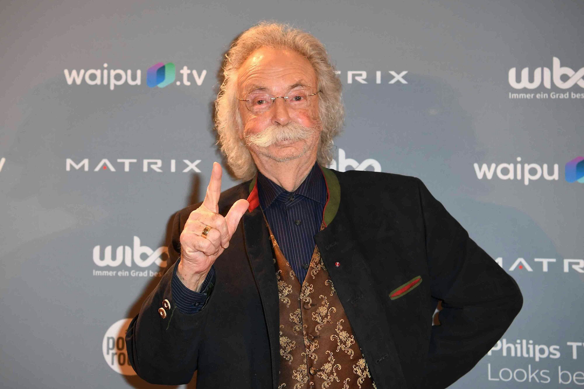 Jean Pütz steht vor einer Fotowand im Hotel Adlon.