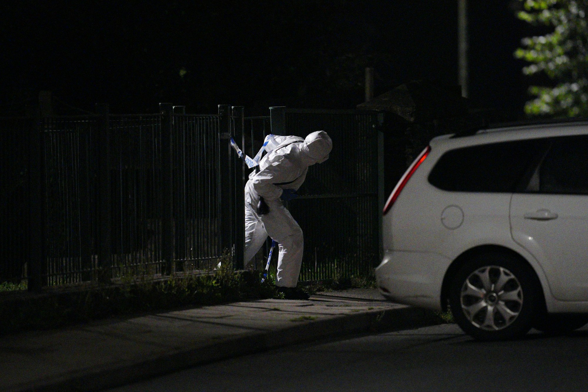 Ein Beamter in einem forensischen Anzug geht durch ein Tor in der Royal Navy Avenue in der Nähe eines Tatorts in der Gegend von Keyham.