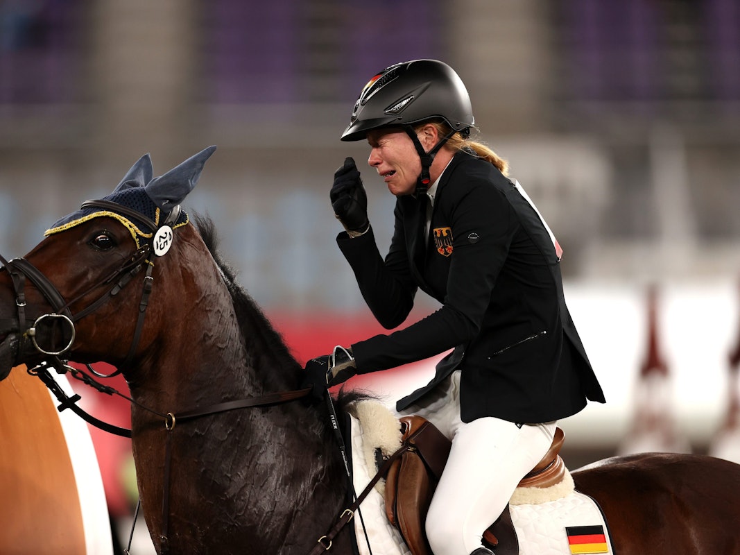 Annika Schleu sitzt bei Olympia weinend auf ihrem Pferd „Saint Boy“.