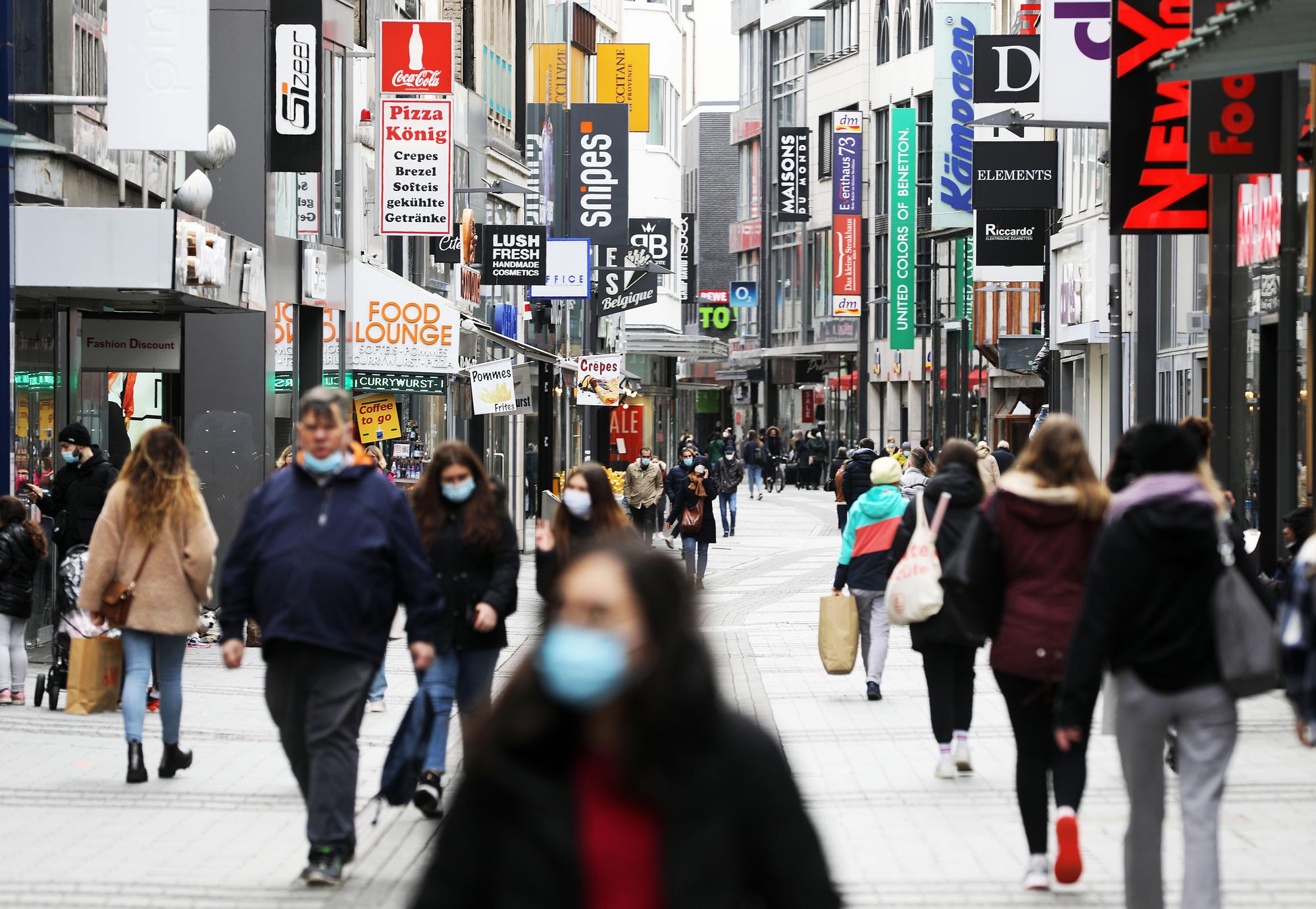 Menschen gehen durch die Kölner Fußgängerzone Hohe Straße.
