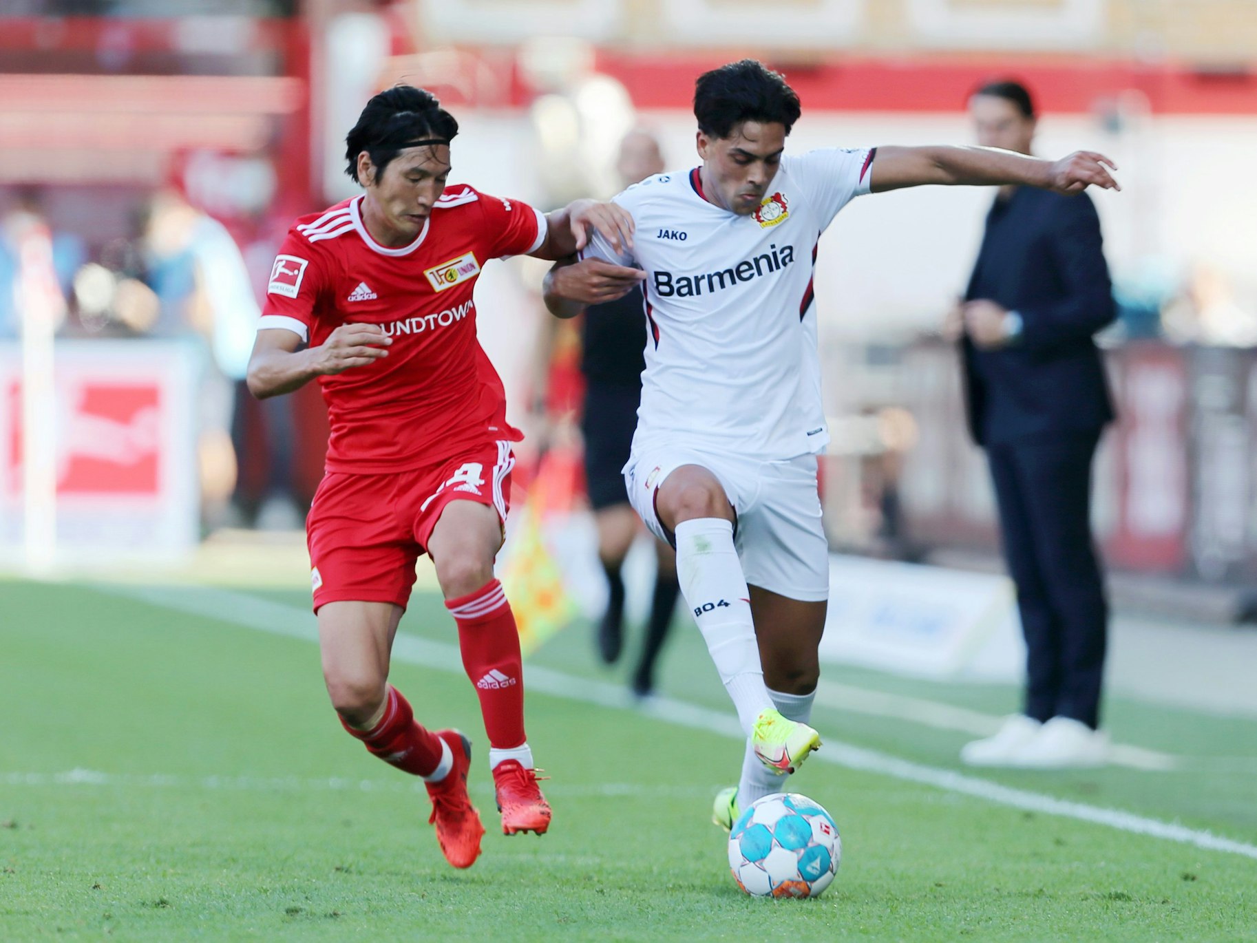 Nadiem Amiri von Bayer Leverkusen im Laufduell mit Genki Haraguchi von Union Berlin.