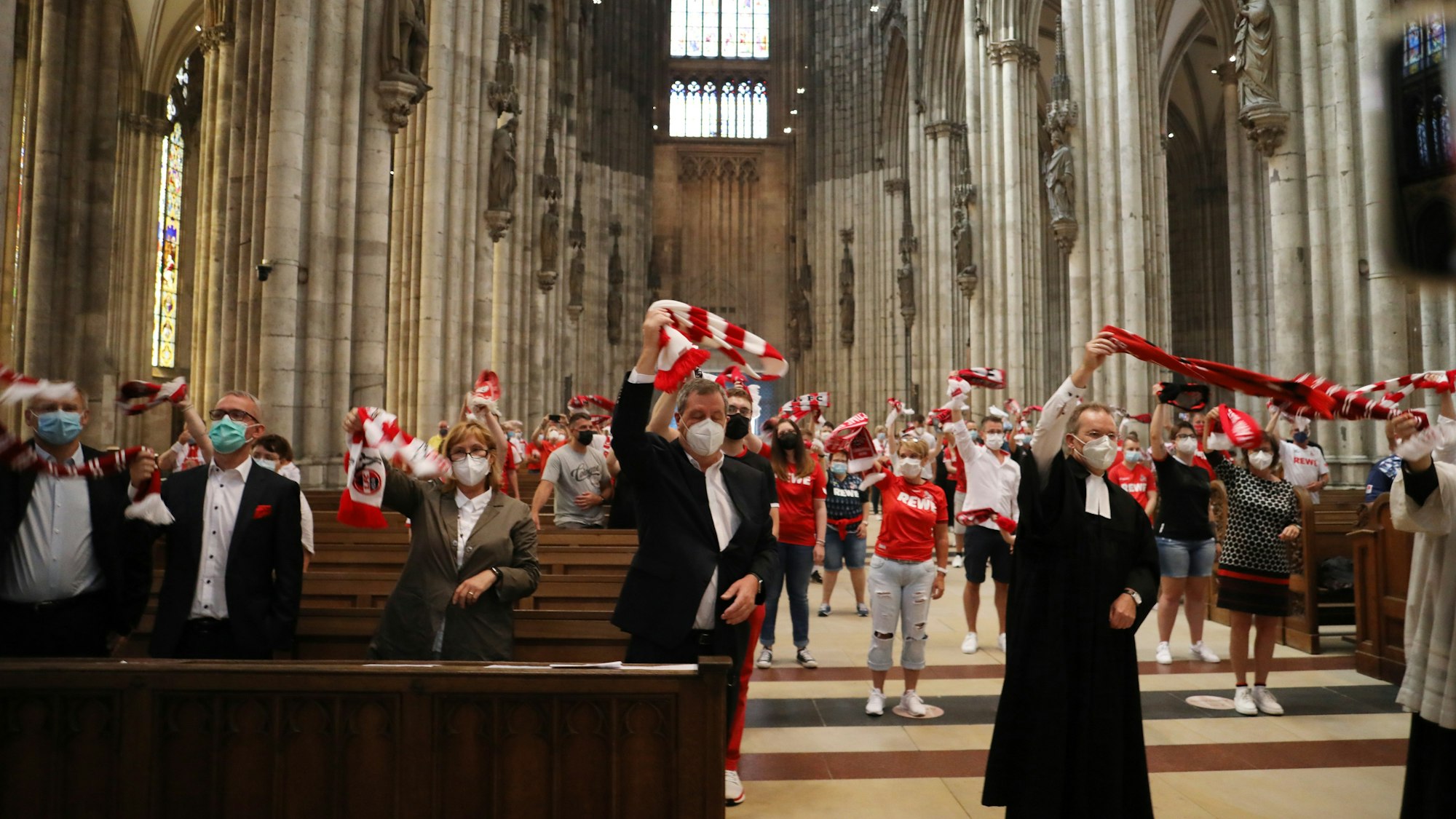 Fans des 1. FC Köln schwenken ihre Schals im Kölner Dom.