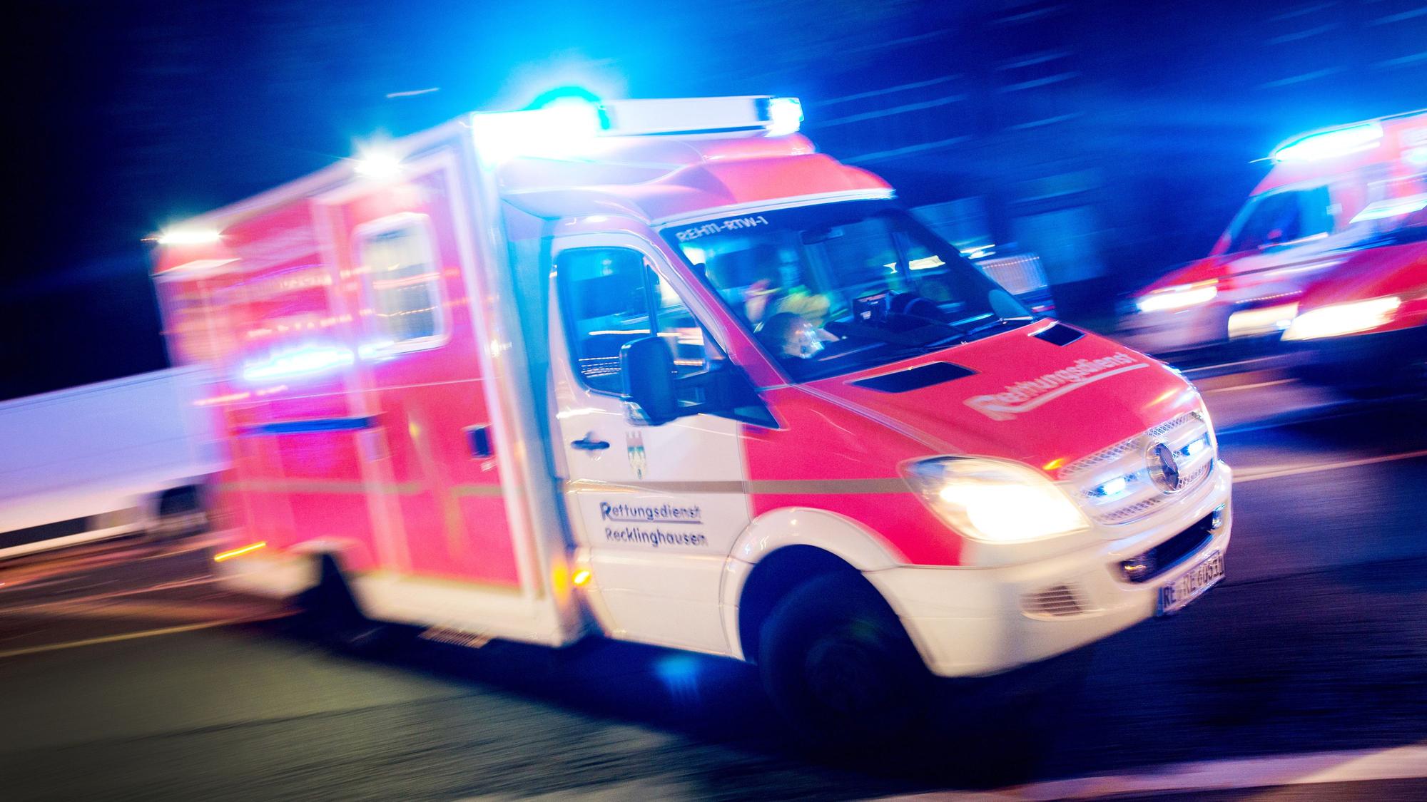 Ein Rettungswagen fährt mit Blaulicht durch eine Straße.