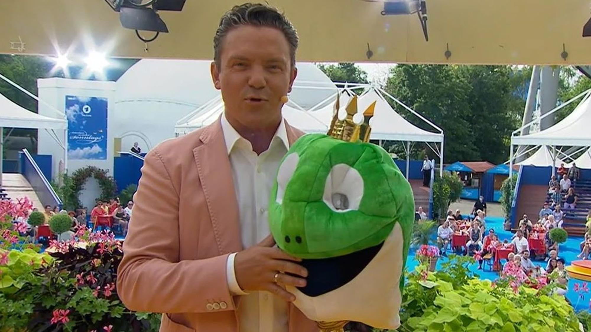 Stefan Mross steht am 15. August bei „‚Immer wieder sonntags‘“ mit einem Froschkopf auf der Bühne