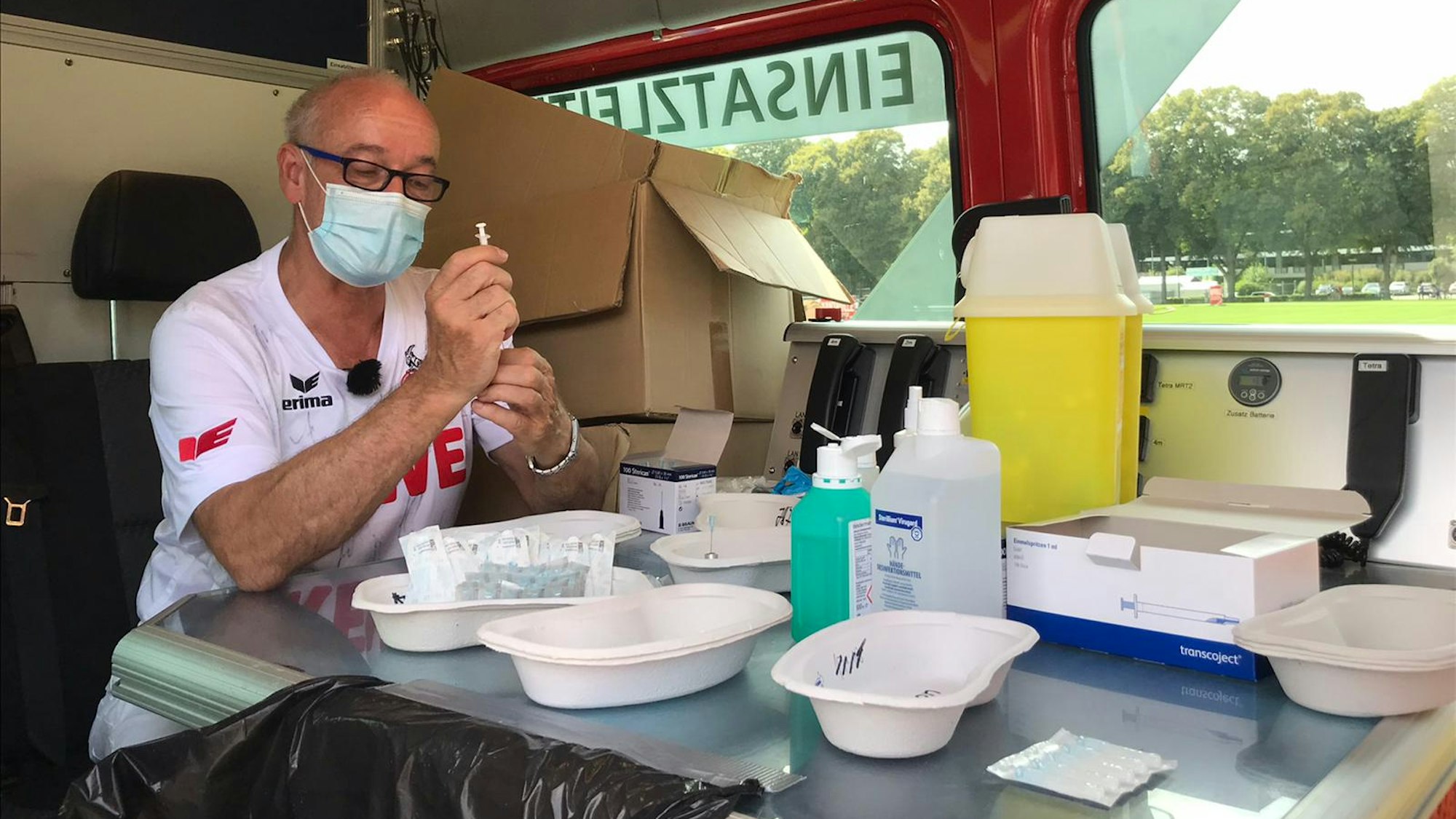 Dr. Jürgen Zastrow, Leitender Impfarzt Köln, zieht Spritzen im Bulli auf den Vorwiesen des Stadions auf.