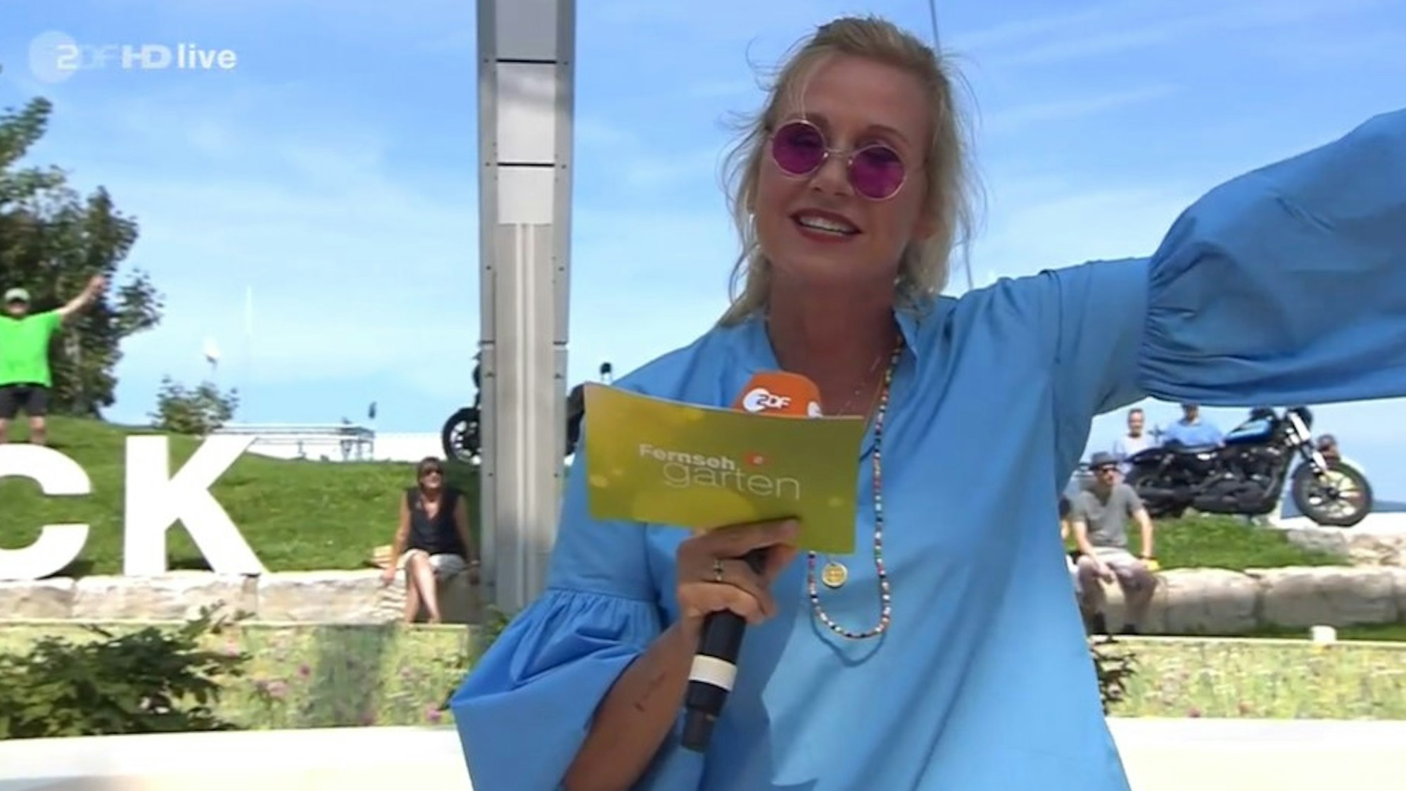 Andrea Kiewel moderiert in einem "Festivaloutfit" mit John Lennon-Brille den ZDF-Fernsehgarten am 15. August