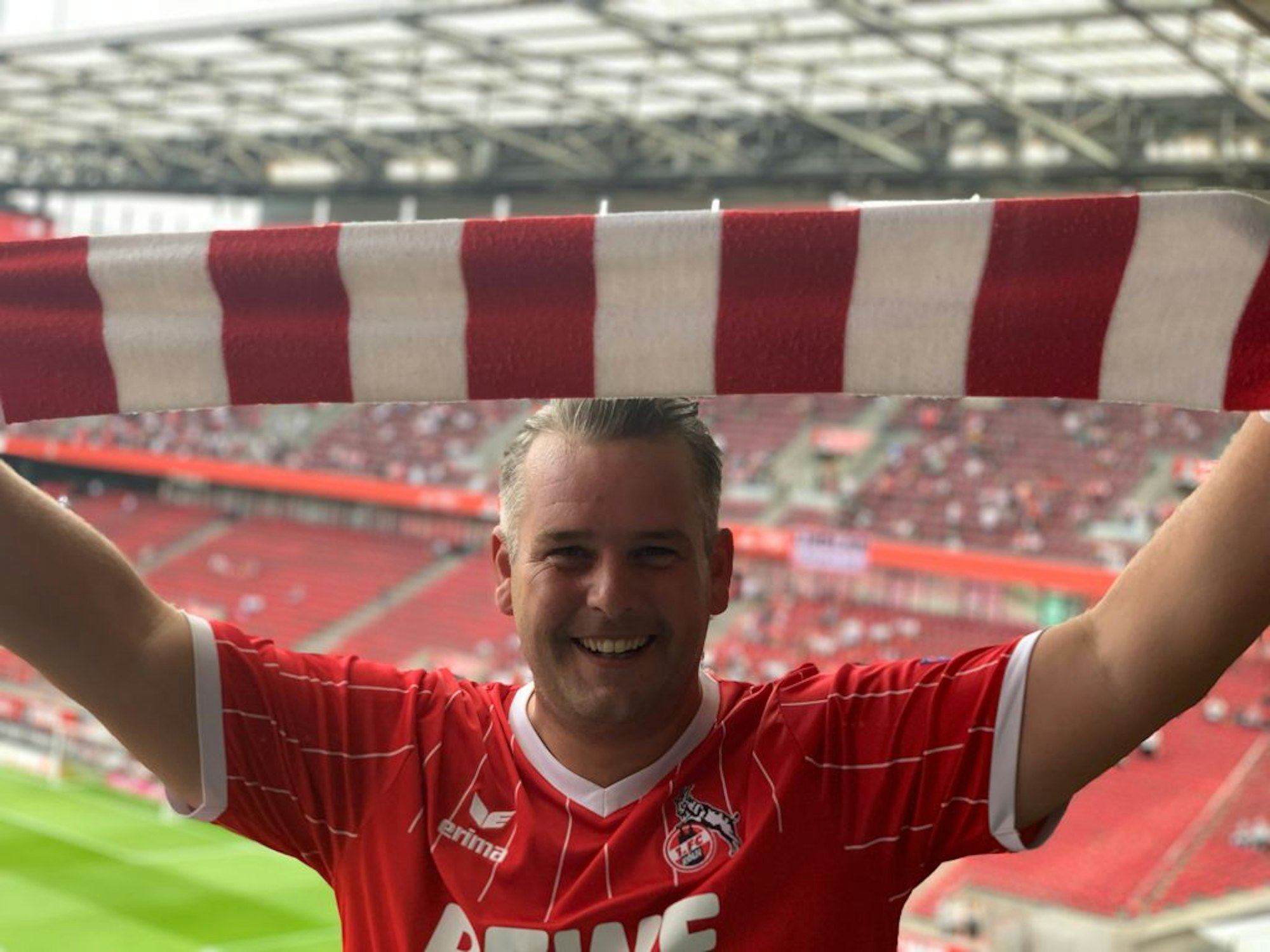 Express-Redakteur Bastian Ebel auf der Tribüne im Rhein-Energie-Stadion mit ausgebreitetem FC-Schal.
