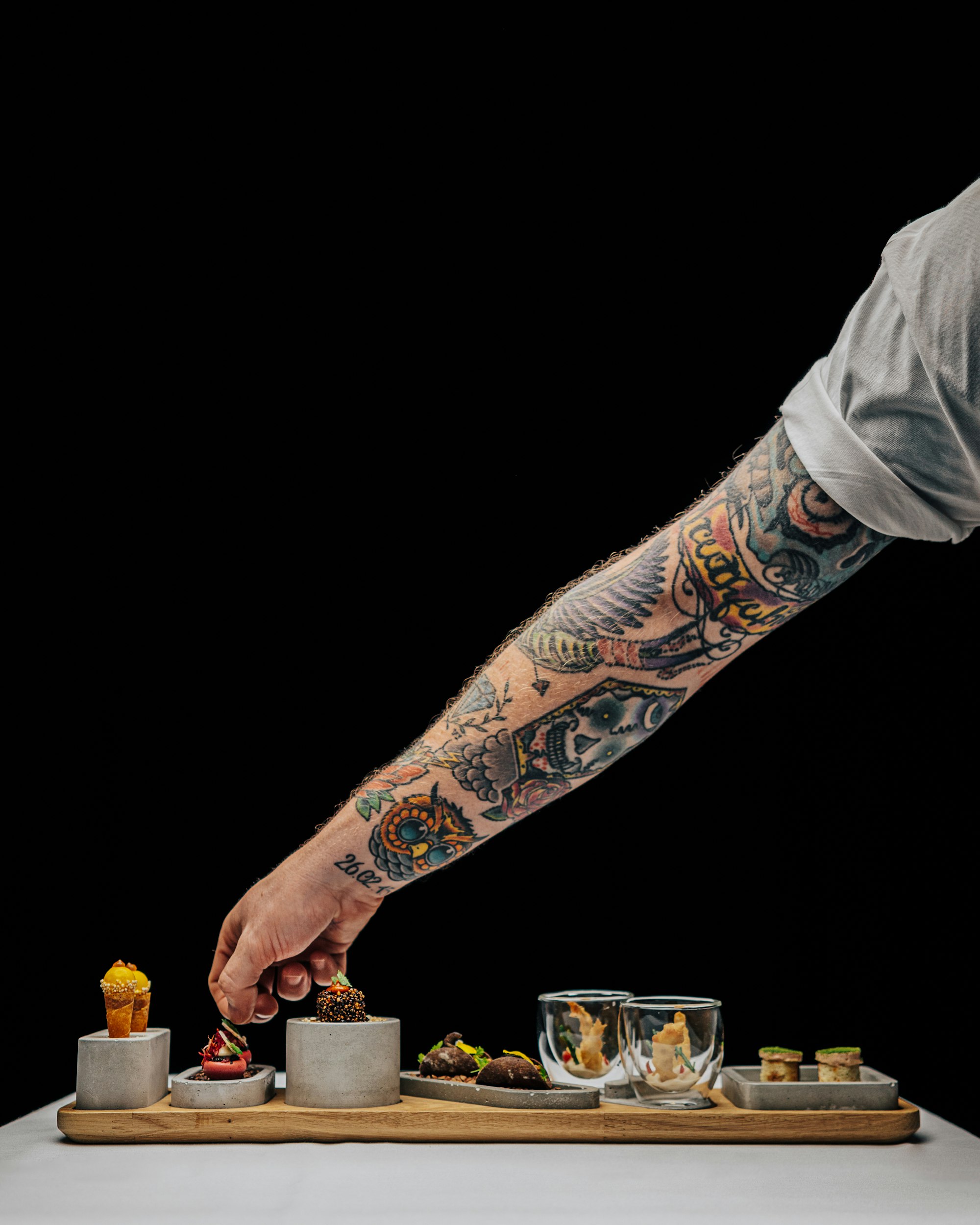 Auf einem Holztablett stehen sechs angerichtete Speisen.