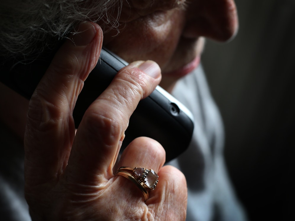 Eine ältere Frau telefoniert mit einem schnurlosen Festnetztelefon. Viele ältere Menschen fallen immer wieder auf den sogenannten Enkeltrick herein.