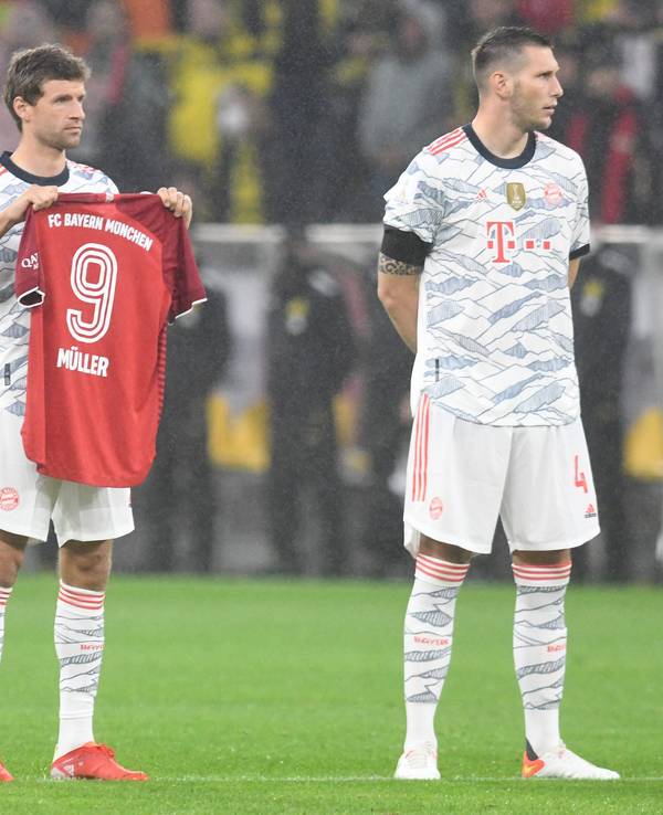 Thomas Müller hält ein Trikot in die Luft