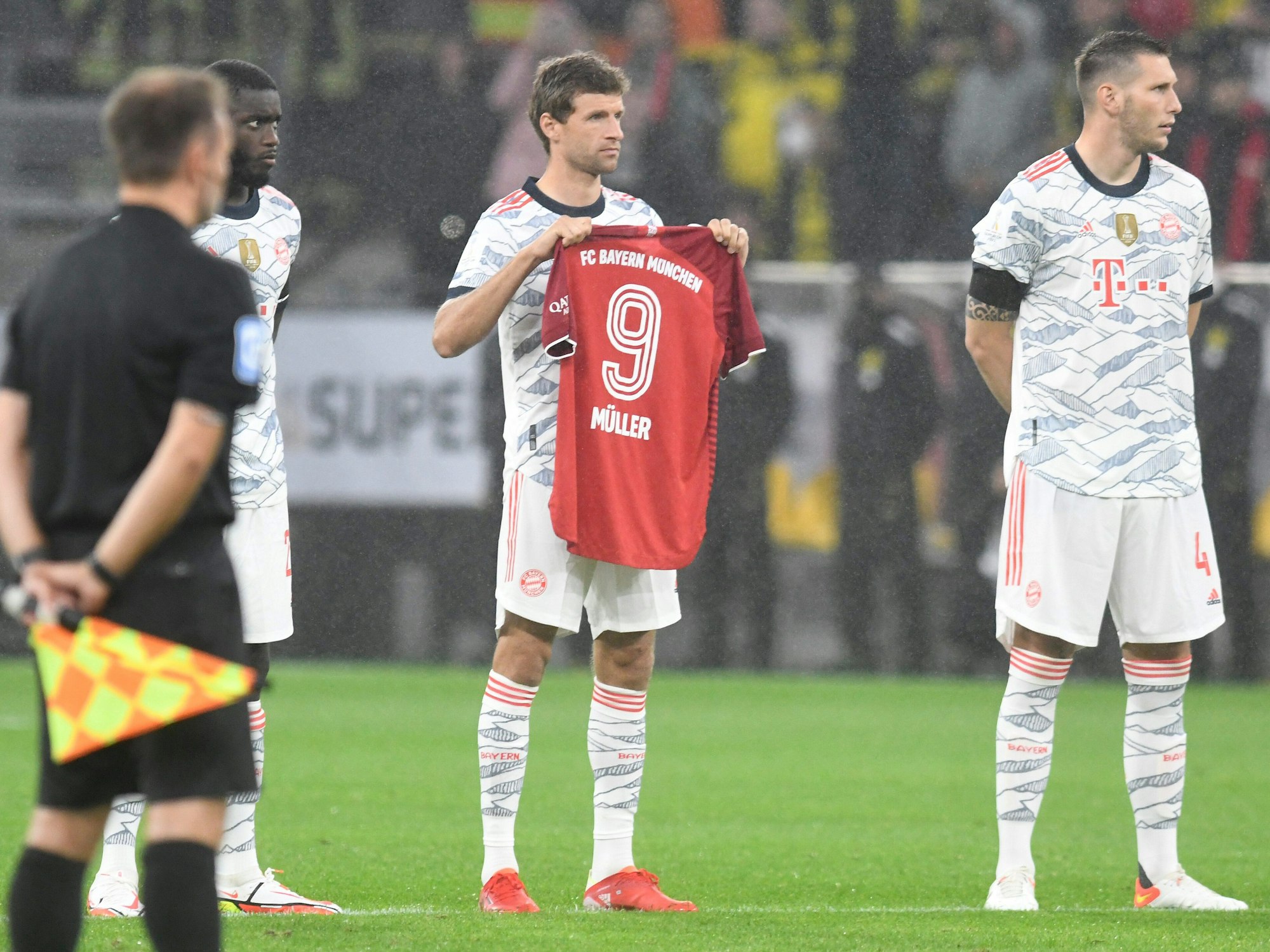 Thomas Müller hält ein Trikot in die Luft