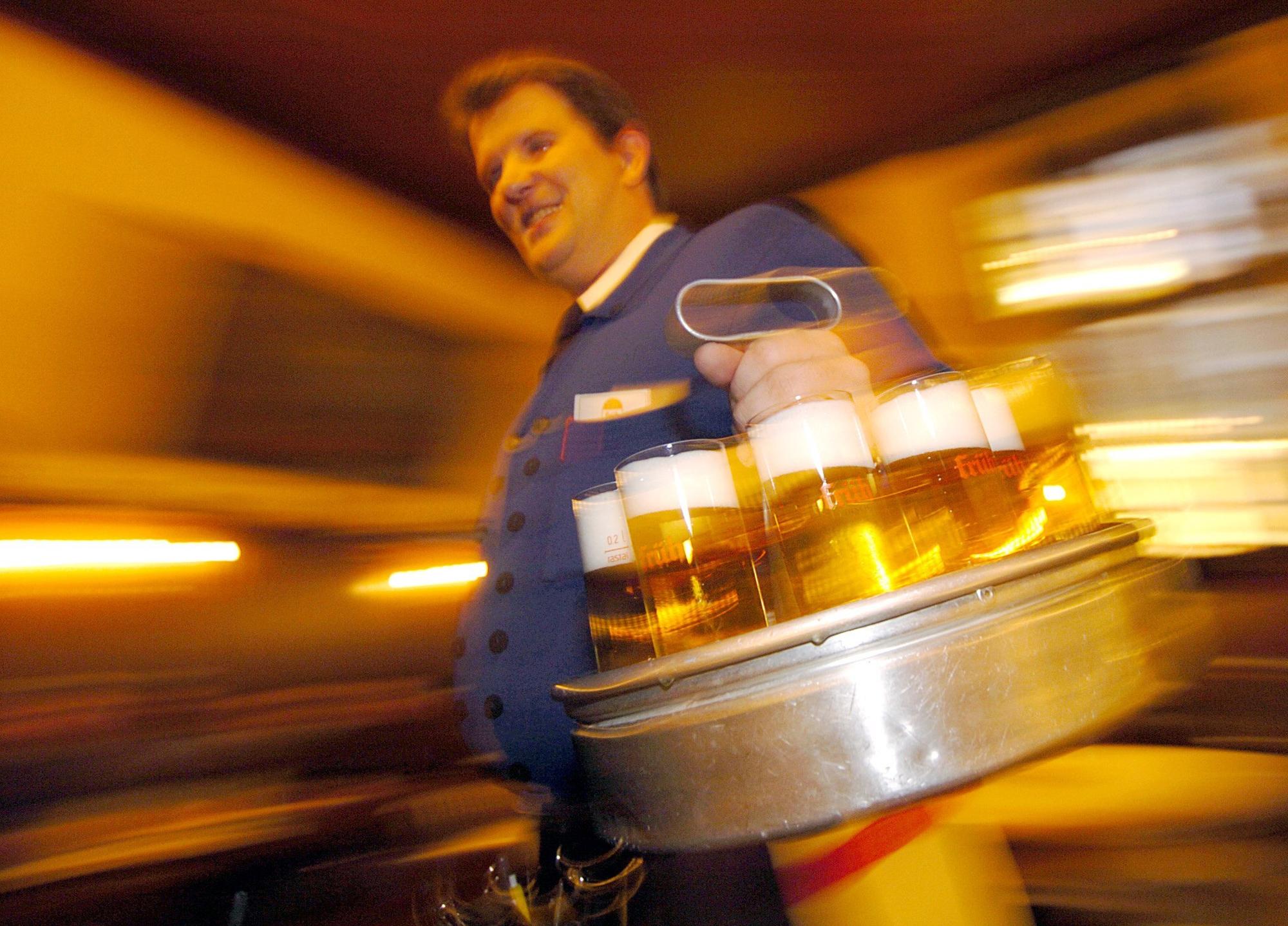 Ein Köbes, ein Wirt in einem Kölsch-Brauhaus in der Kölner Innenstadt serviert Kölsch.
