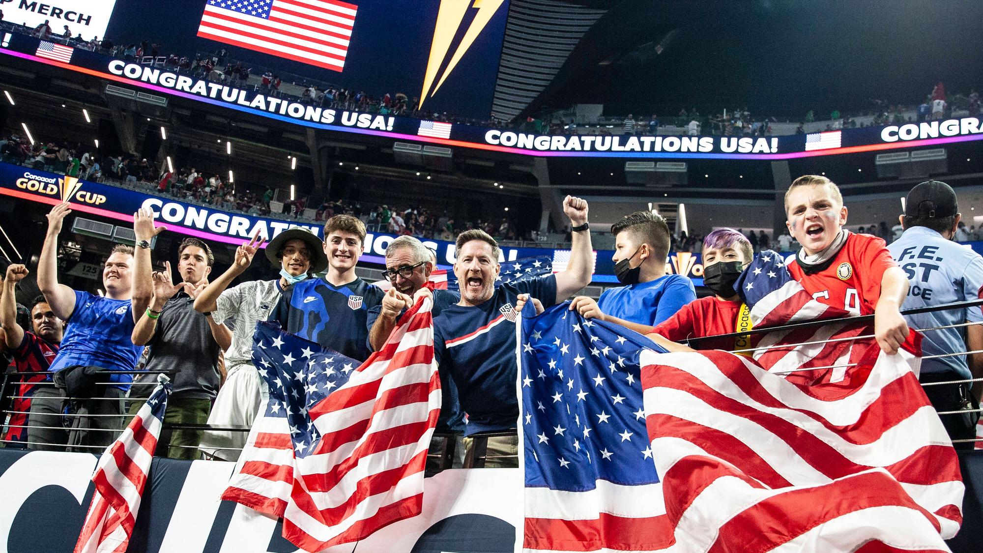 Fußballfans jubeln und schwenken US-amerikanische Flaggen.