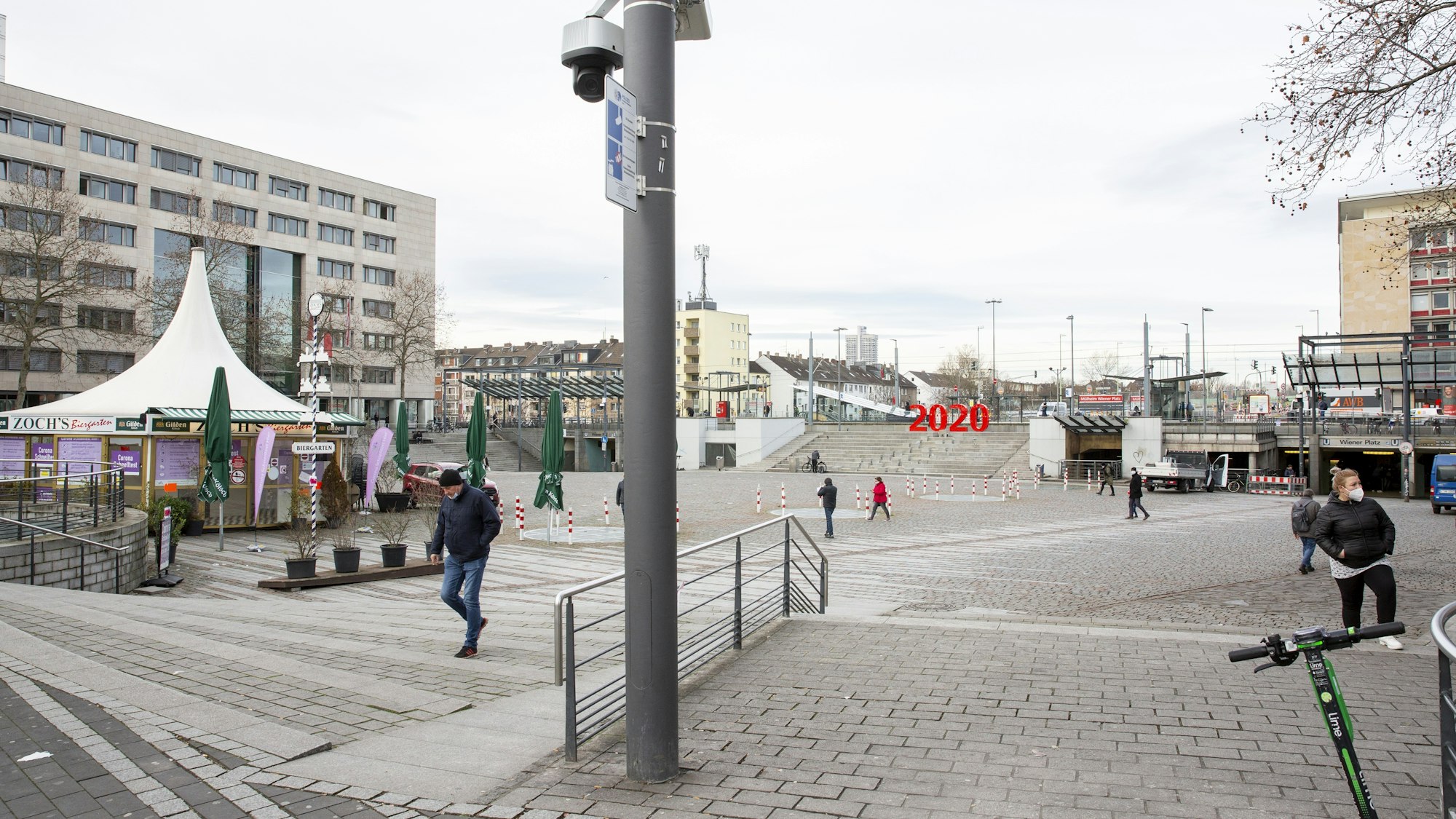 Menschen gehen über die große gepflasterte Fläche des Wiener Platzes, links im Hintergrund ein mehrstöckiges Gebäude, in dem sich das Bürgerzentrum befindet.