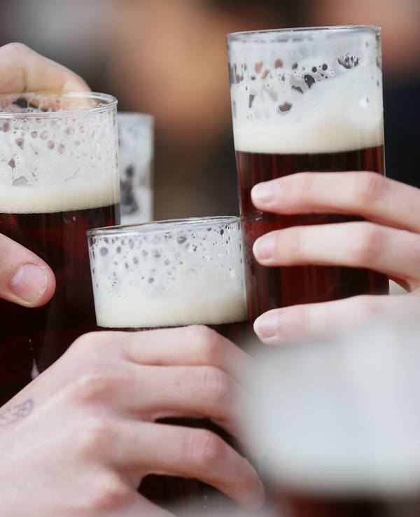 Gäste stoßen an einem Tisch im Außenbereich eines Lokals mit Altbier an.