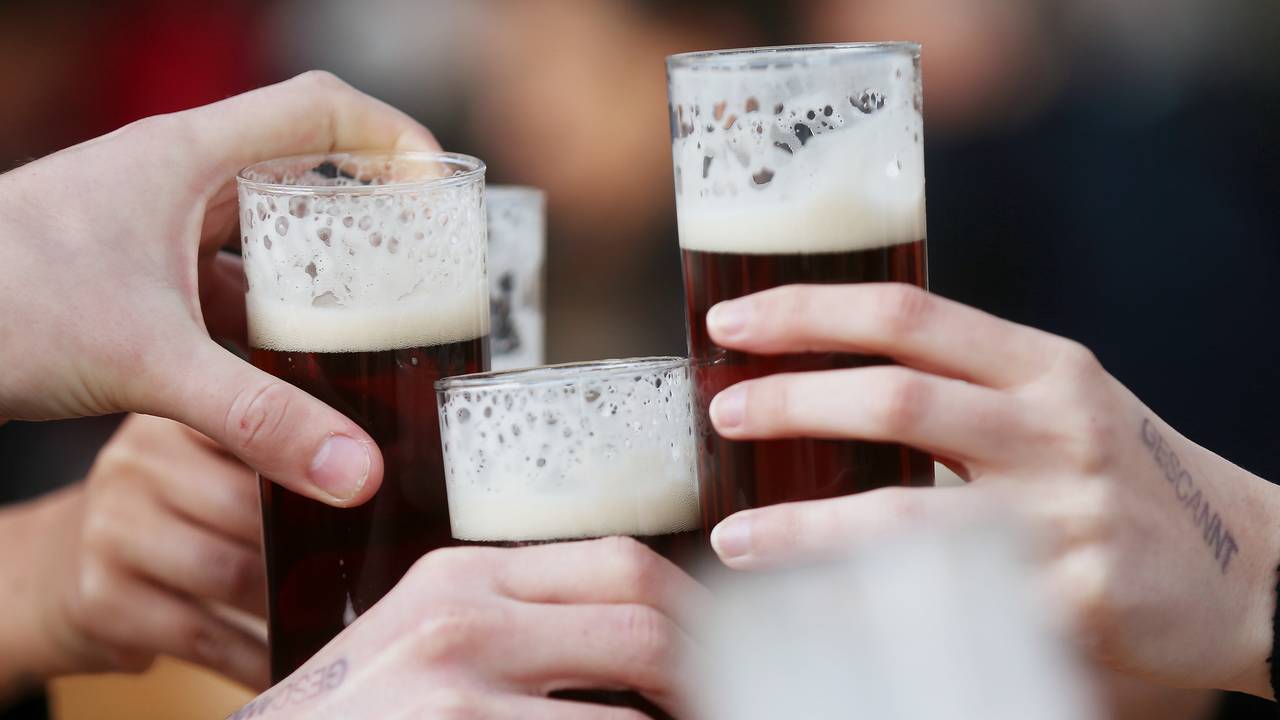 Gäste stoßen an einem Tisch im Außenbereich eines Lokals mit Altbier an.
