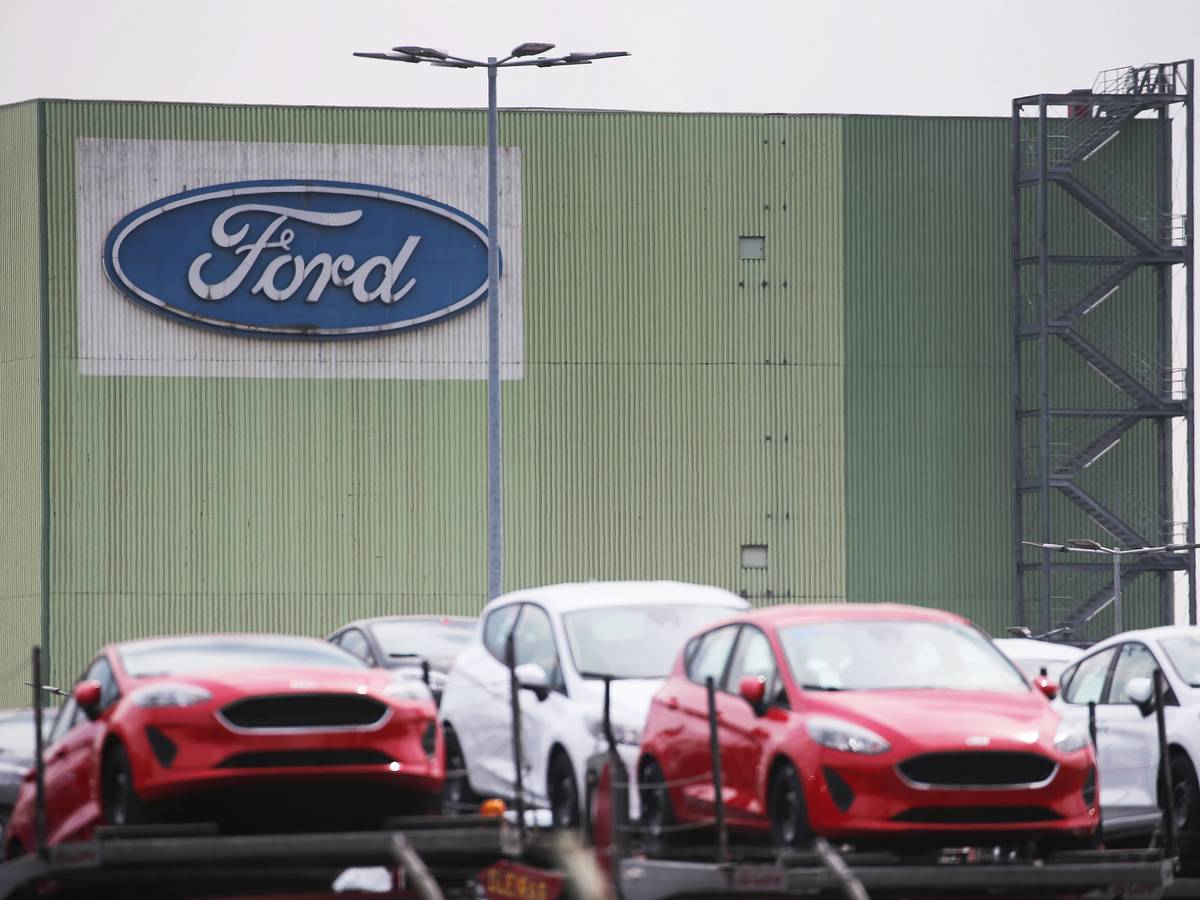 Neu gebaute Autos stehen auf Lastwagen vor dem Ford Werk.