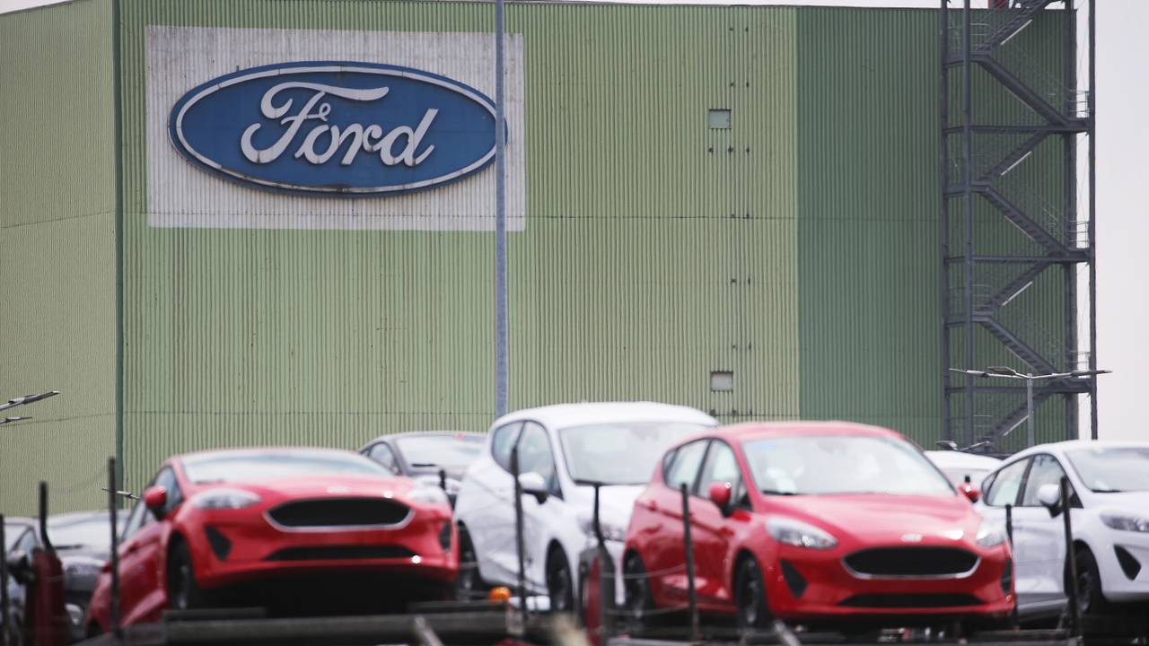 Neu gebaute Autos stehen auf Lastwagen vor dem Ford Werk.
