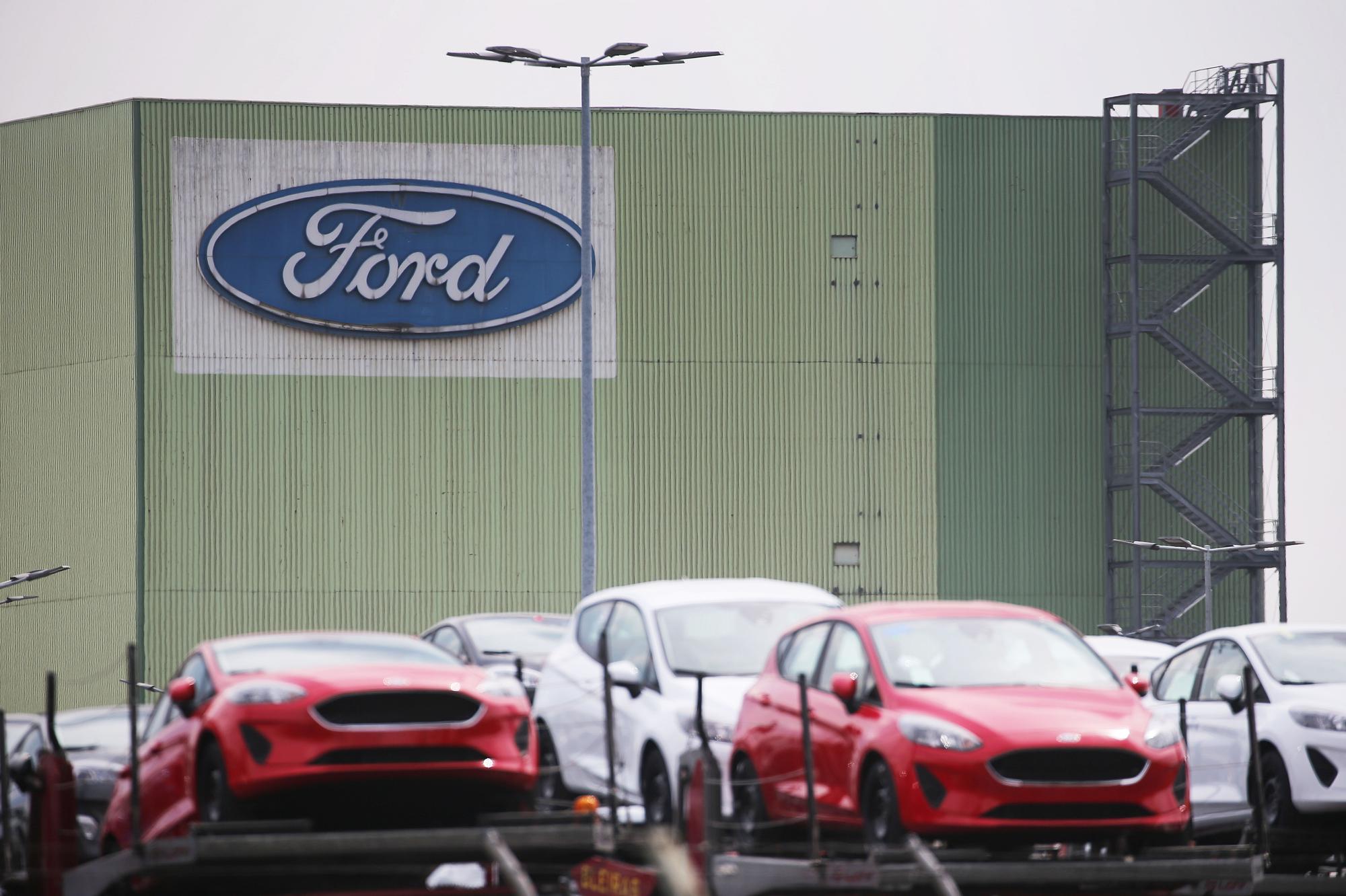 Neu gebaute Autos stehen auf Lastwagen vor dem Ford Werk.
