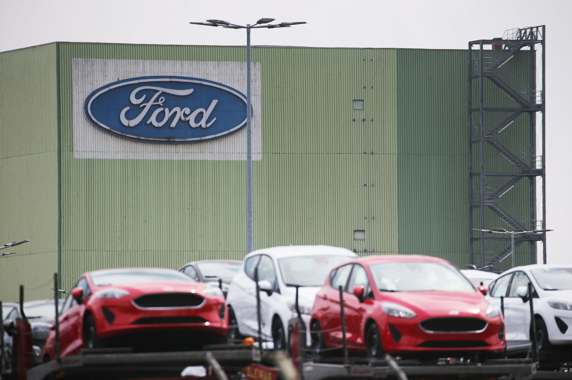 Neu gebaute Autos stehen auf Lastwagen vor dem Ford Werk.