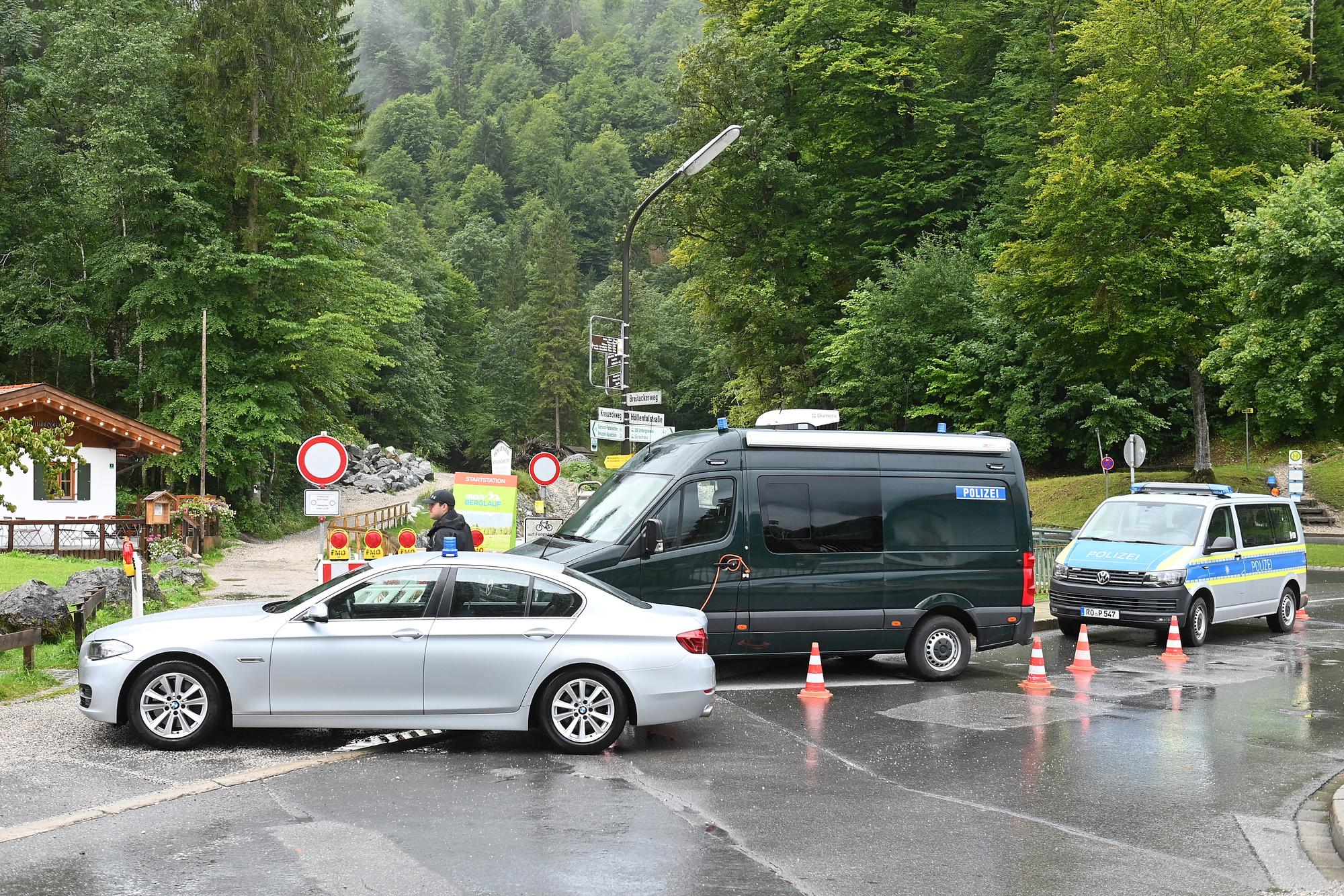Einsatzfahrzeuge der Polizei stehen am Eingang zur Höllentalklamm. Nach der Flutwelle in der Klamm an der Zugspitze geht die Suche nach zwei Vermissten weiter.
