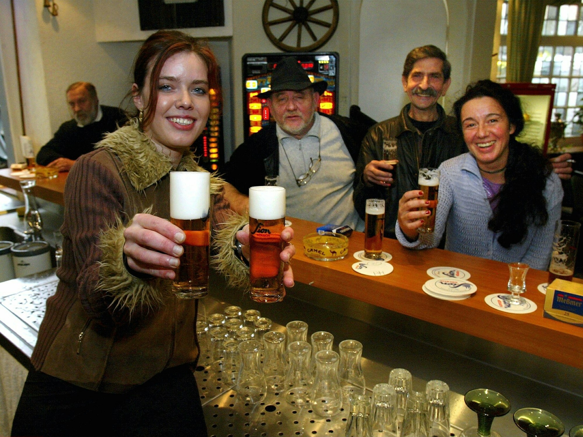 Eine Frau reicht an der Theke Kölsch.