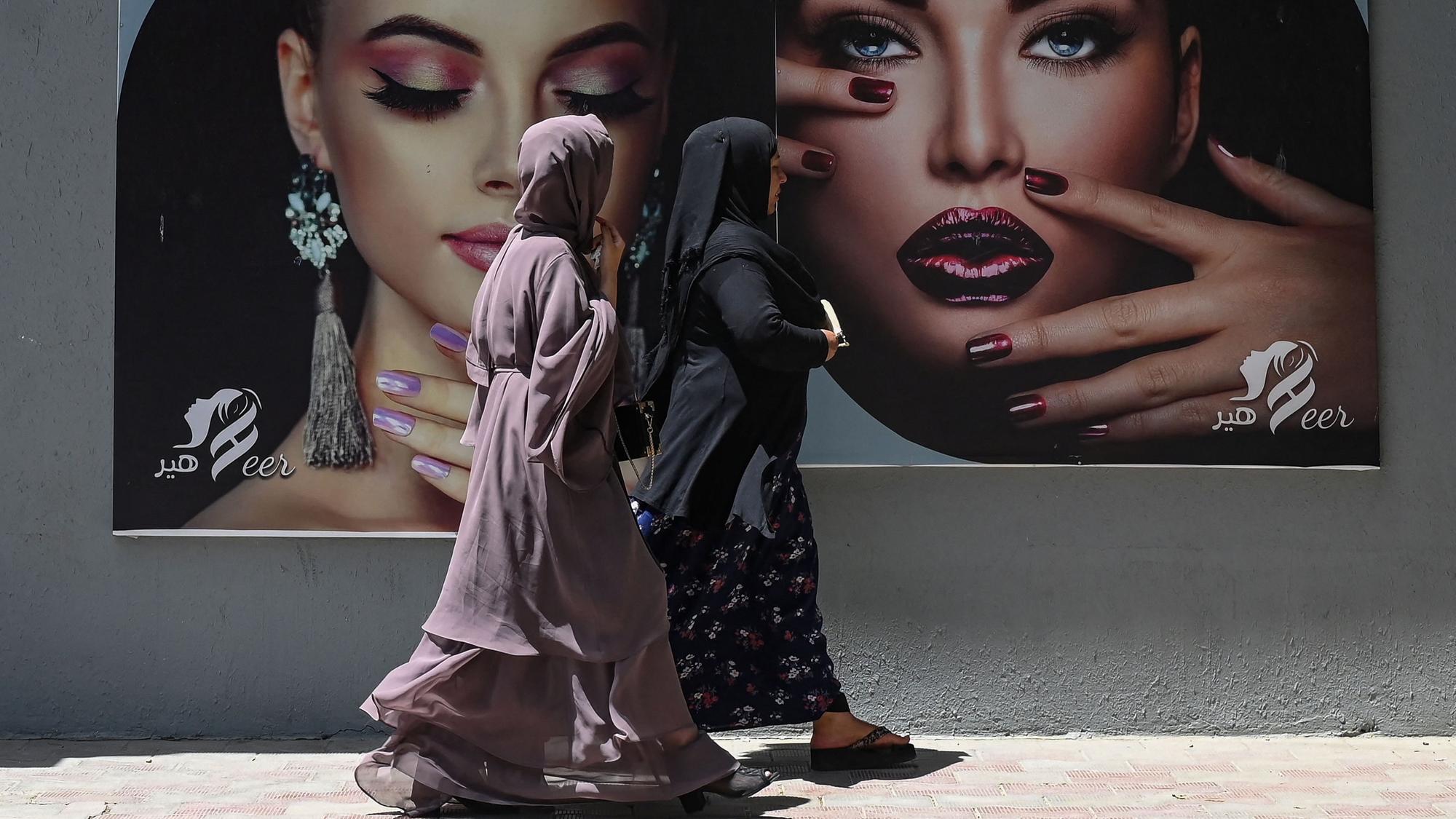 Frauen laufen in Kabul an Werbung für einen Beautysalon vorbei.