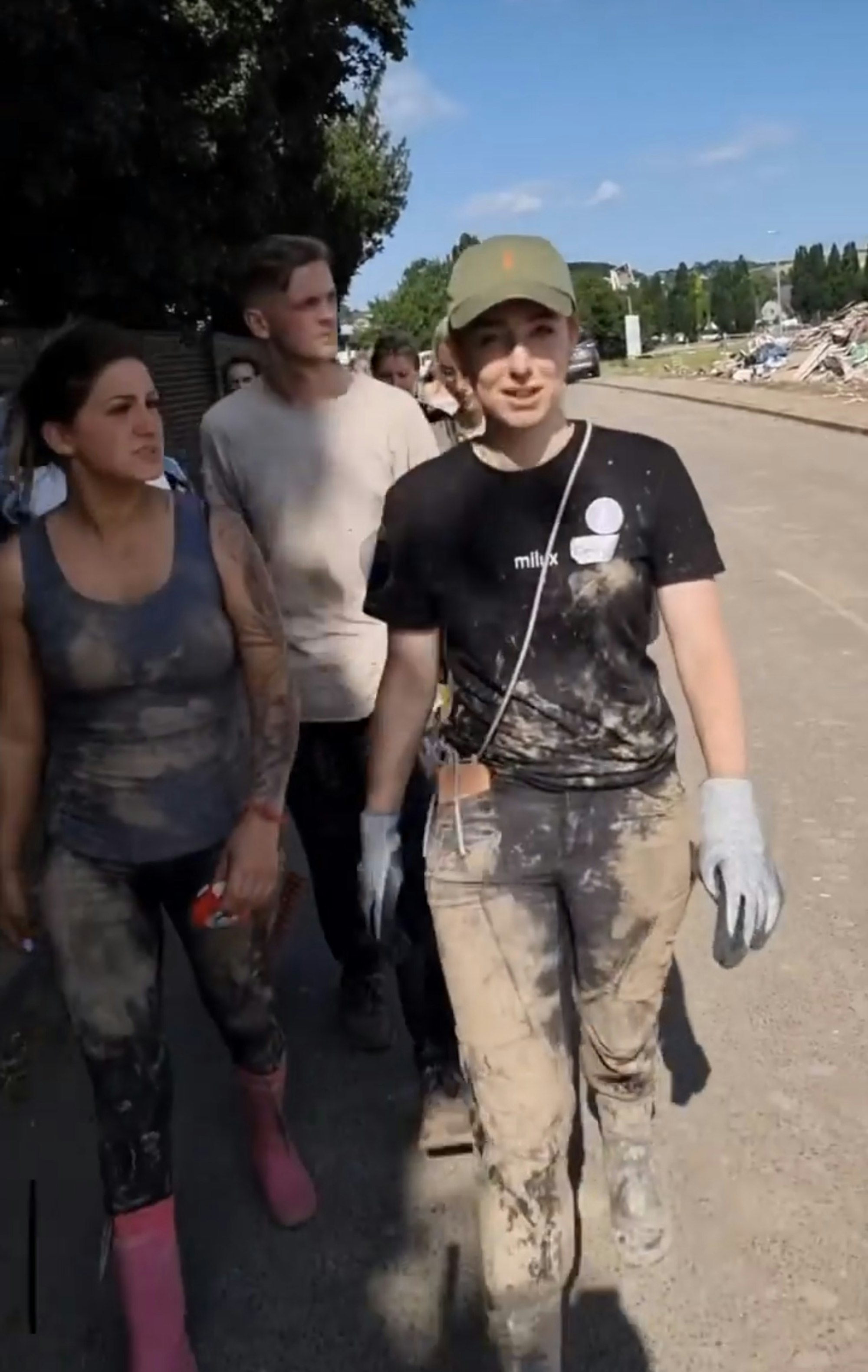 Emily mit verschlammten Klamotten und Handschuhen mit zwei weiteren Helfenden.