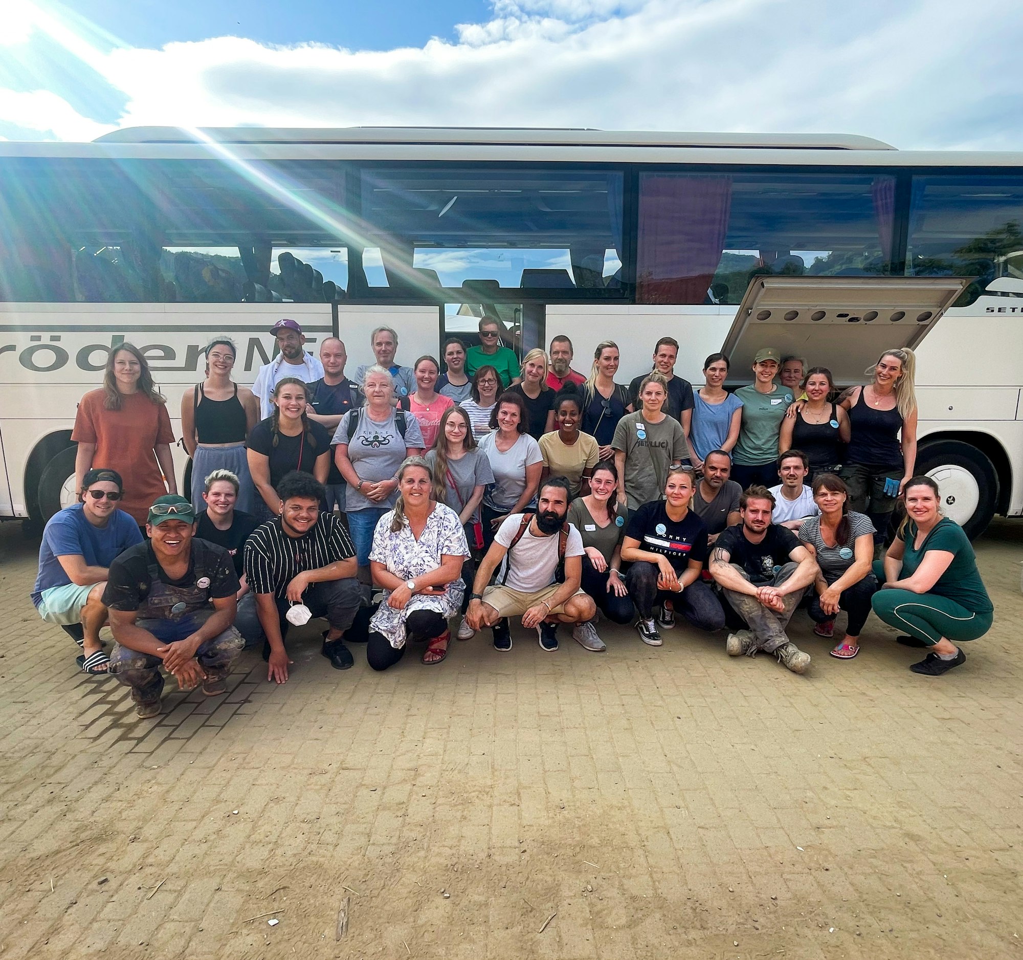 Helfer knien und stehen vor einem Reisebus.