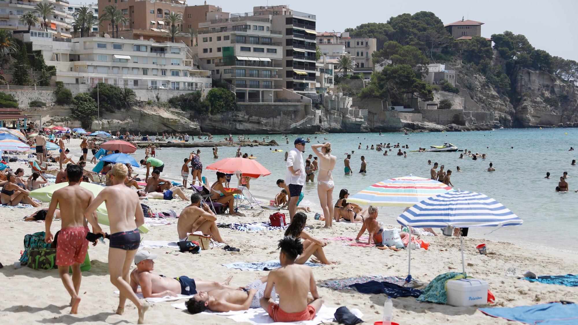 Einheimische und Touristen kühlen sich im Meer am Strand Cala Major in Palma de Mallorca ab.