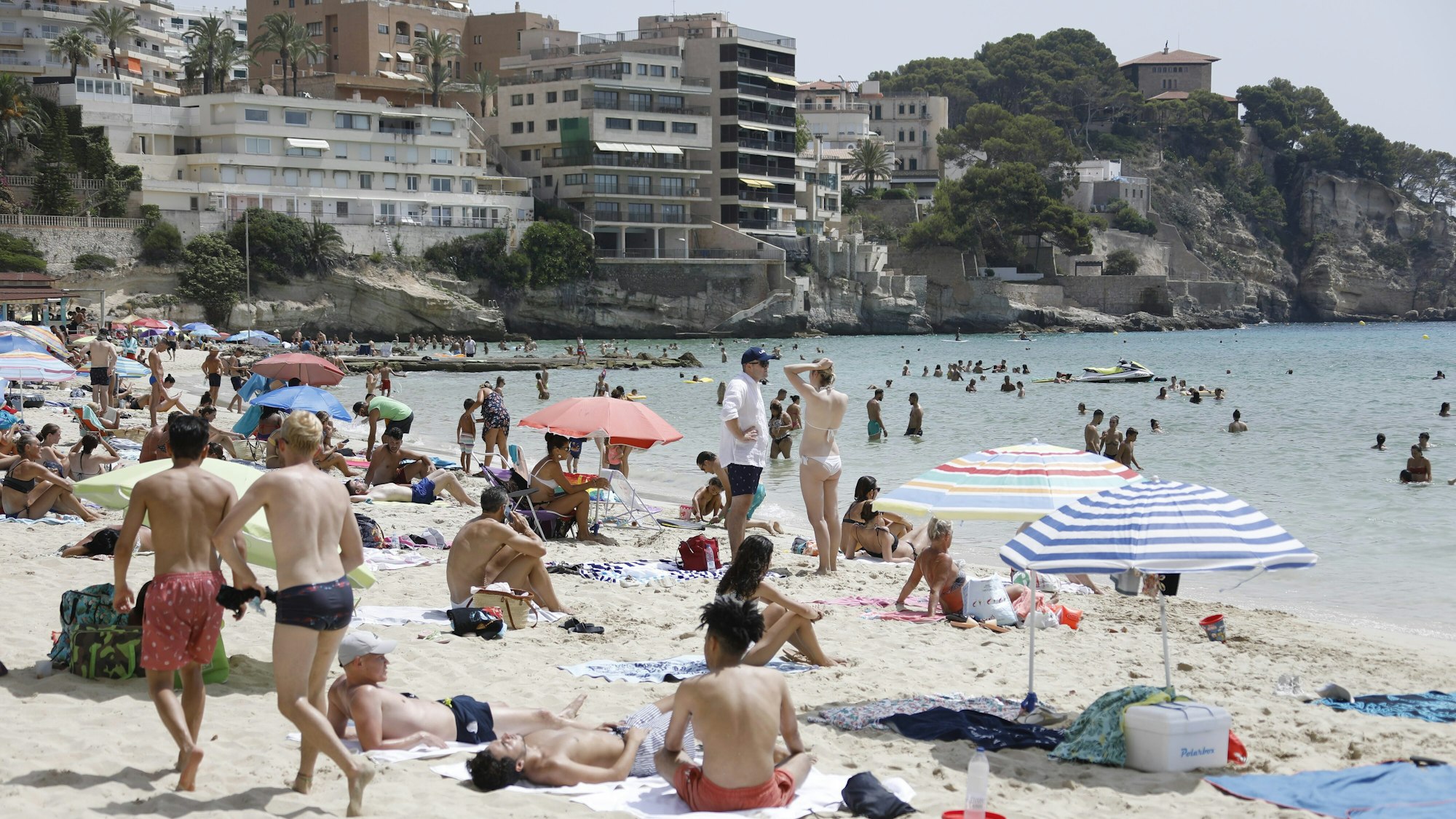 Einheimische und Touristen kühlen sich im Meer am Strand Cala Major in Palma de Mallorca ab.