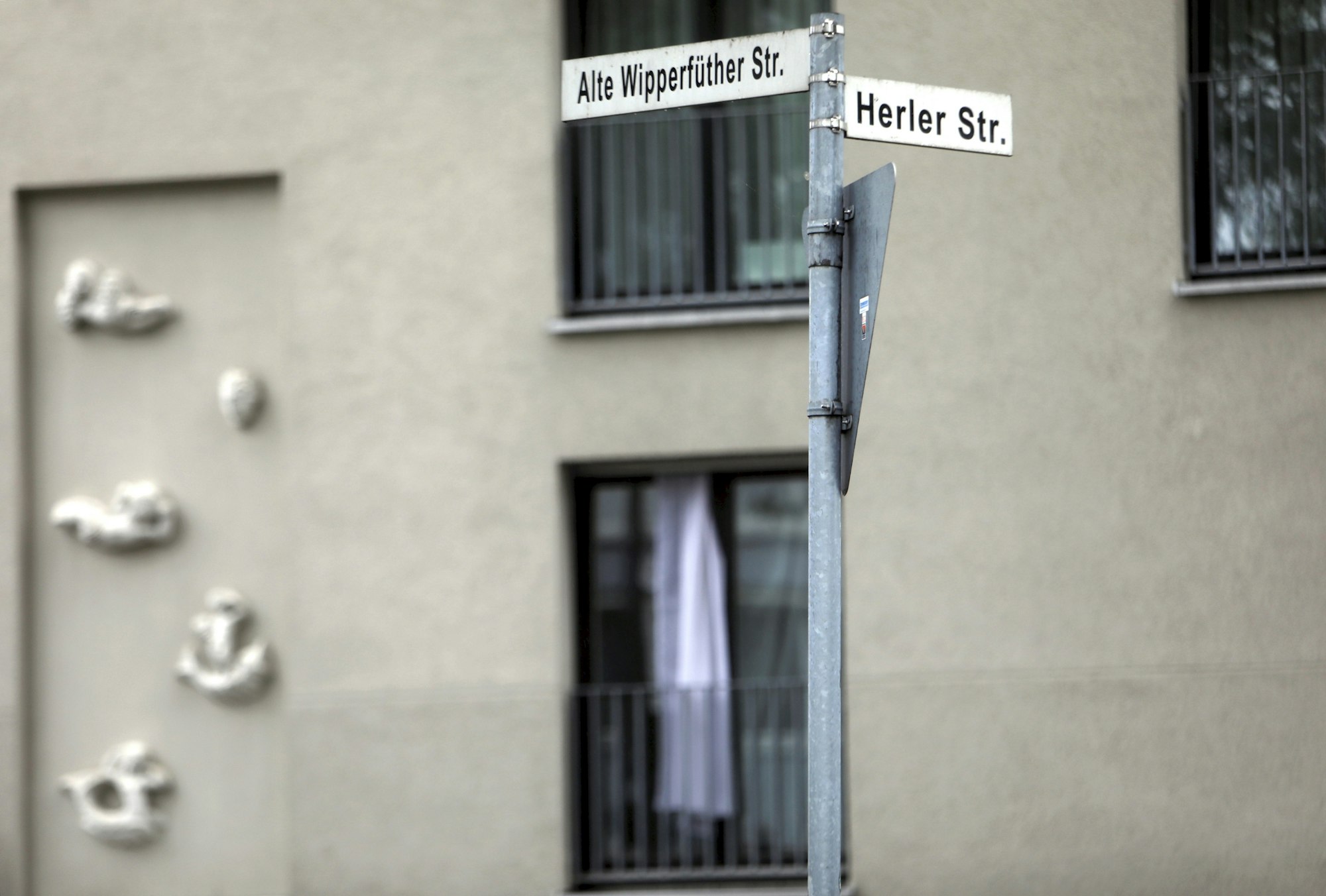 Straßenschilder an der Kreuzung Alte Wipperfürther Straße/Herler Straße in Köln-Buchheim. Bei Alte Wipperfürther Straße fehlt auf dem Straßenschild ein „r“.