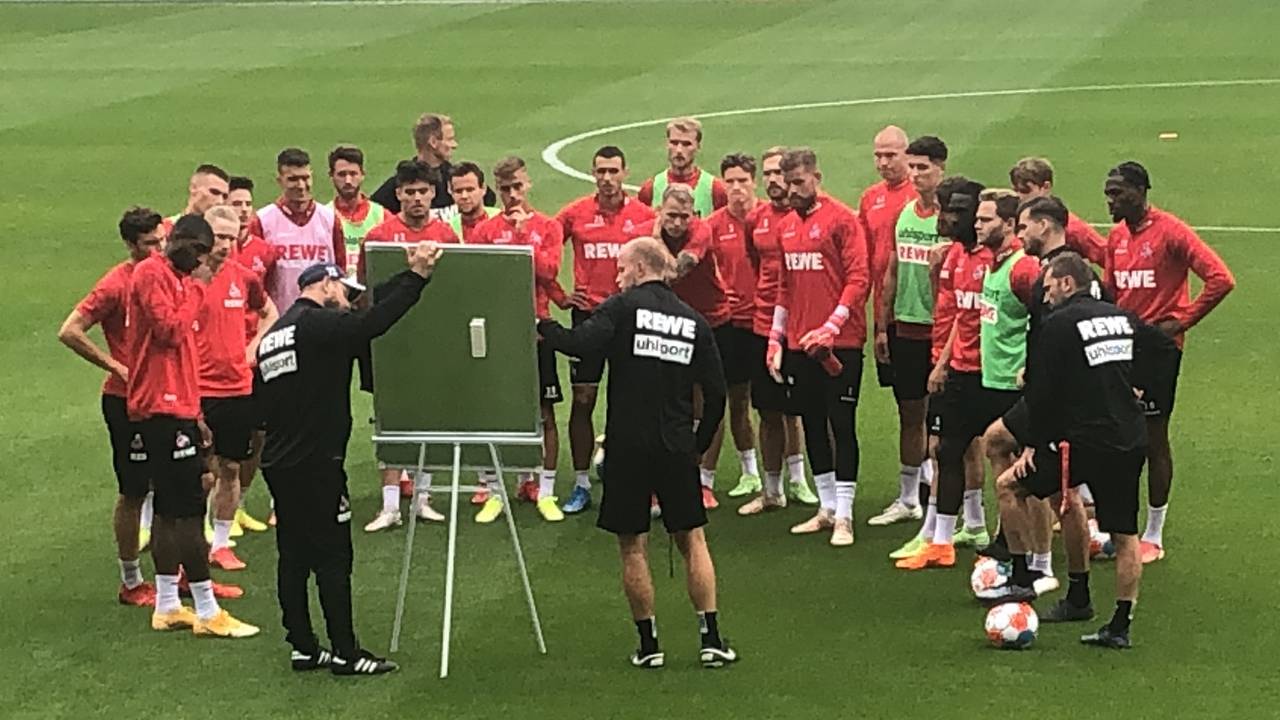 Steffen Baumgart und Assistent Kevin McKenna versammeln die Mannschaft im Training des 1. FC Köln vor der Taktiktafel.