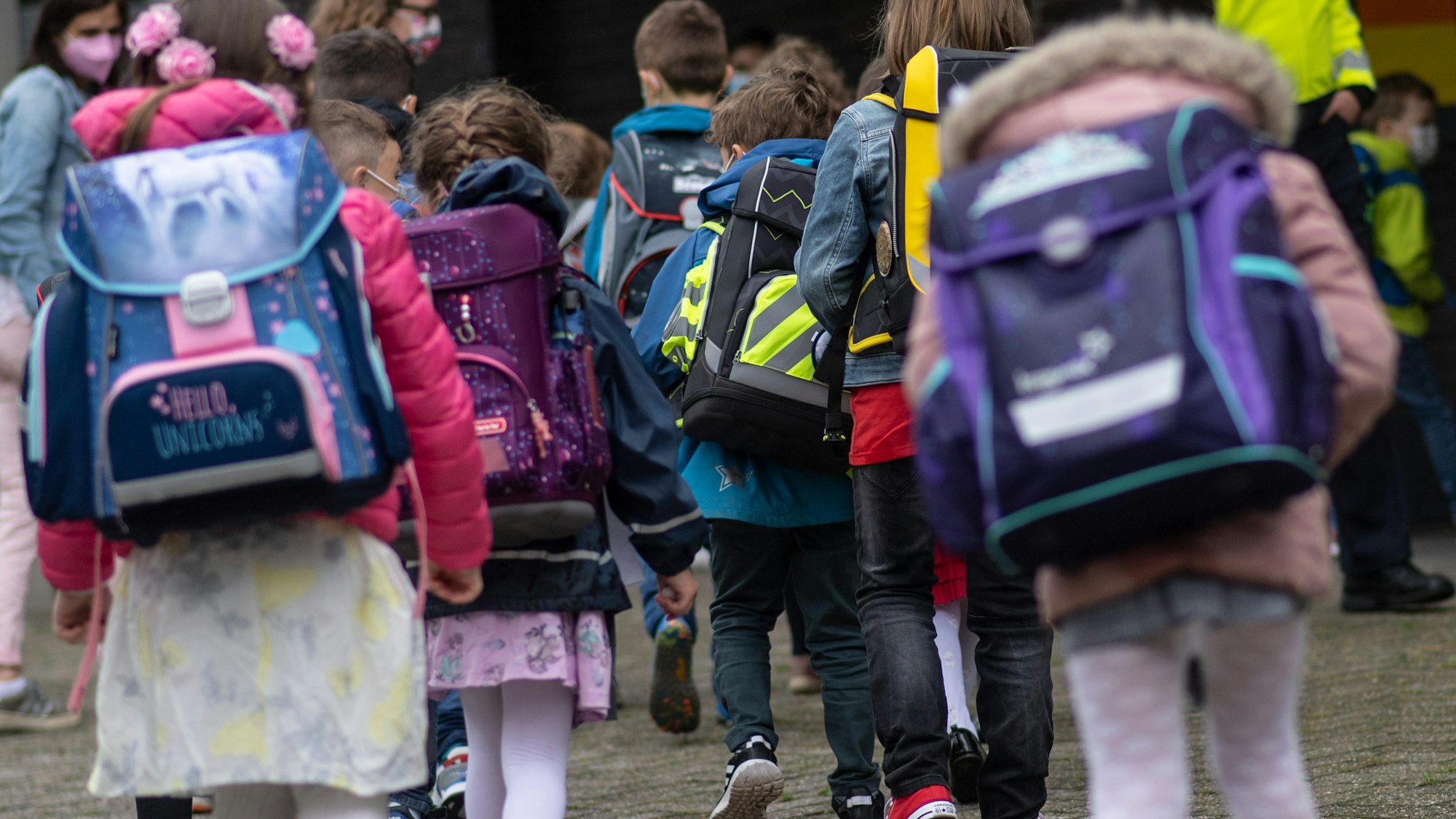 Kinder mit ihren Schultaschen warten bei der Einschulung der Grundschule Ferdinand-Lasalle auf den gemeinsamen Gang in ihr Klassenzimmer.