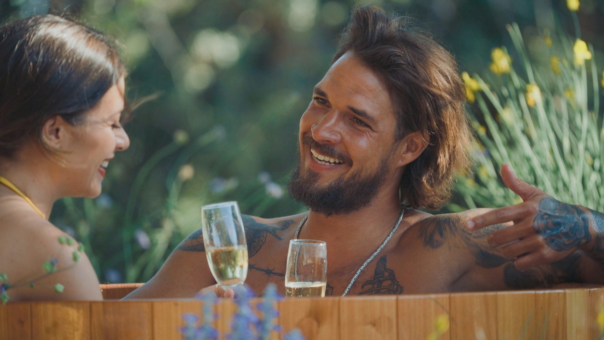 Bachelorette Maxime und Zico sitzen sich mit Sektgläsern in der Hand gegenüber.