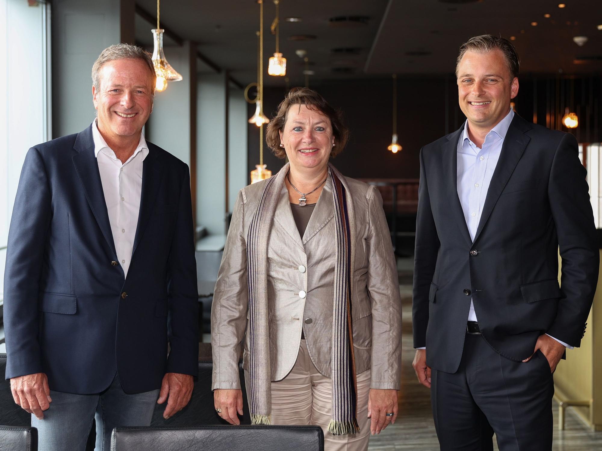 Michael Garvens, Anne Henk-Hollstein und Dr. Konrad Adenauer blicken im Pullman-Hotel in die Kamera.