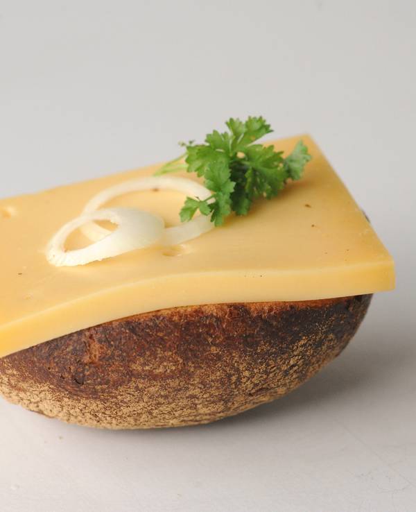 So lieben die Kölnerinnen und Kölner den Halven Hahn - mit Röggelchen. Ein halbes Roggenbrötchen ist mit einer Scheibe Käse, Zwiebelringen und Petersilie belegt.