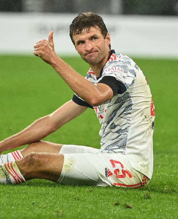 Thomas Müller sitzt auf dem Rasen und reckt den Daumen nach oben.