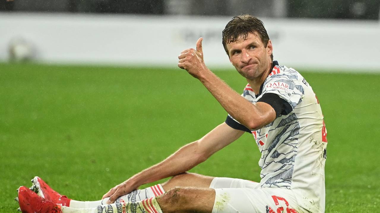 Thomas Müller sitzt auf dem Rasen und reckt den Daumen nach oben.