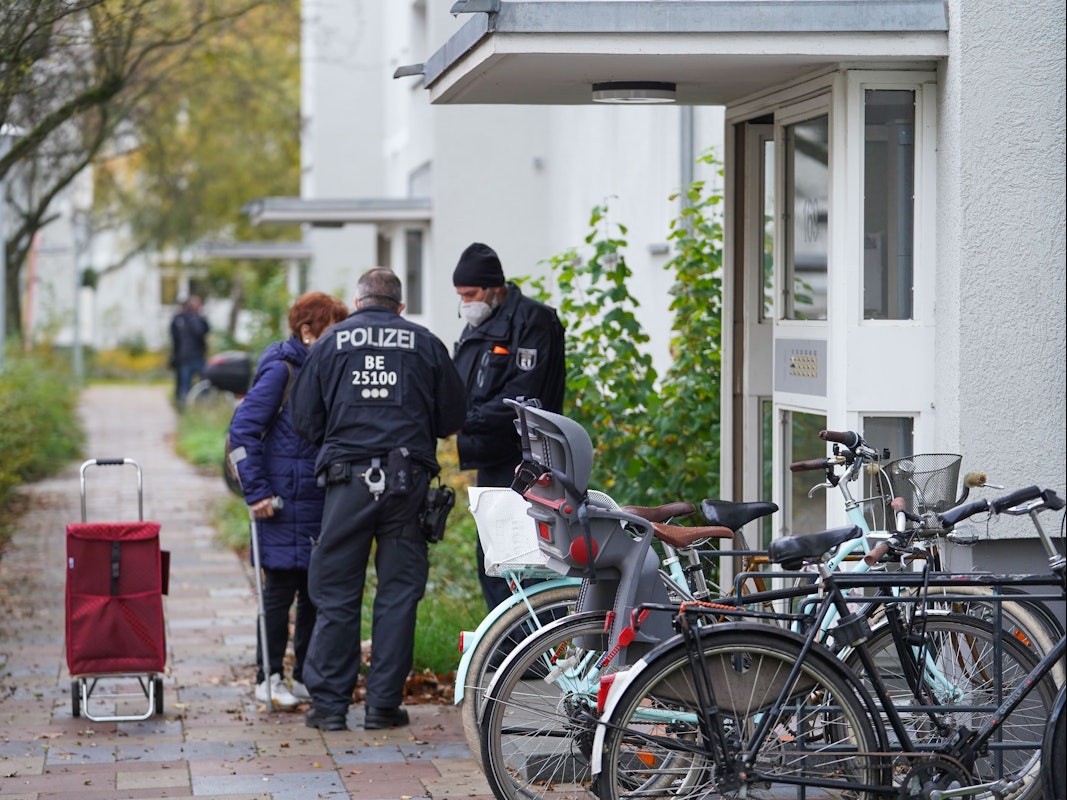 Zwei Polizisten sprechen vor der Haustür mit älterer Frau.