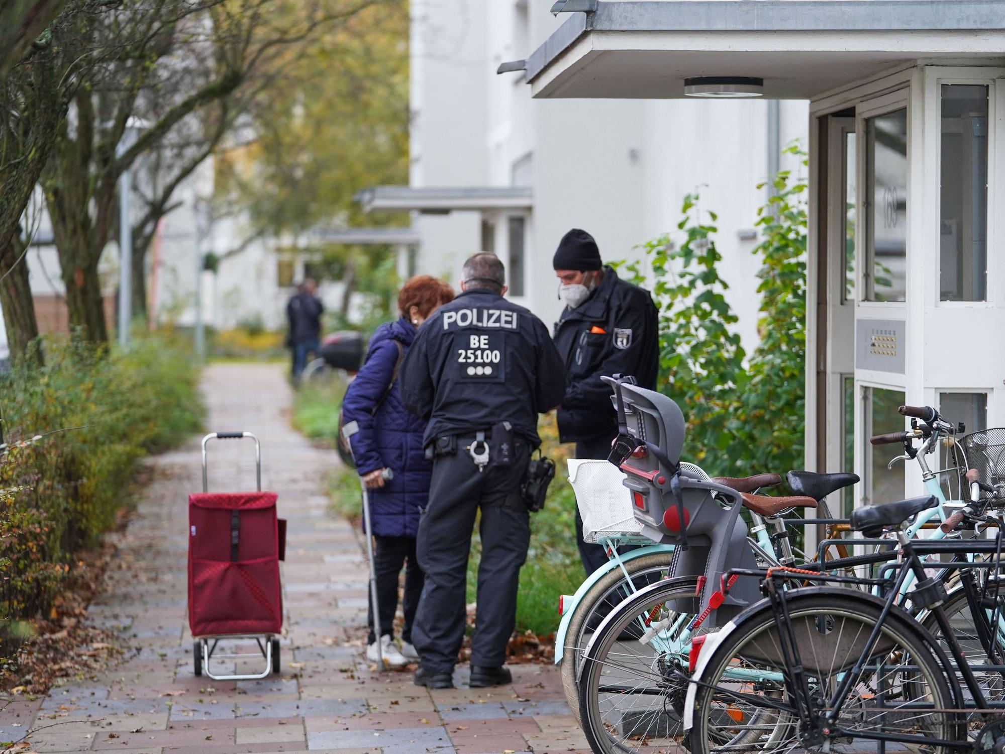 Zwei Polizisten sprechen vor der Haustür mit älterer Frau.