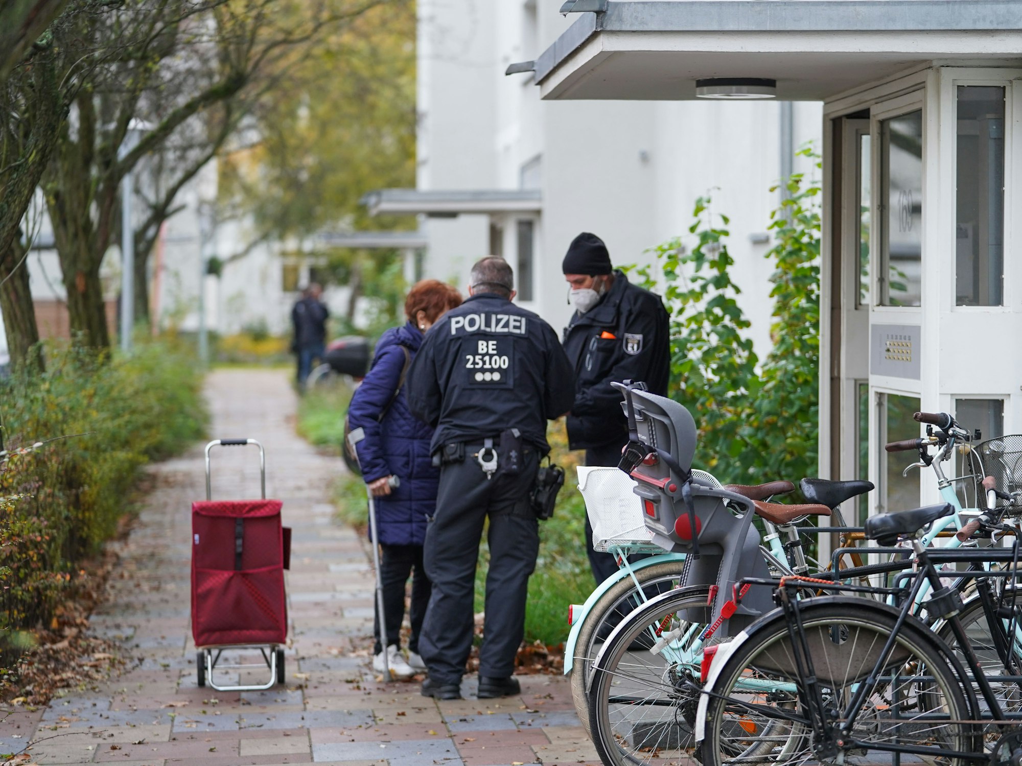 Zwei Polizisten sprechen vor der Haustür mit älterer Frau.