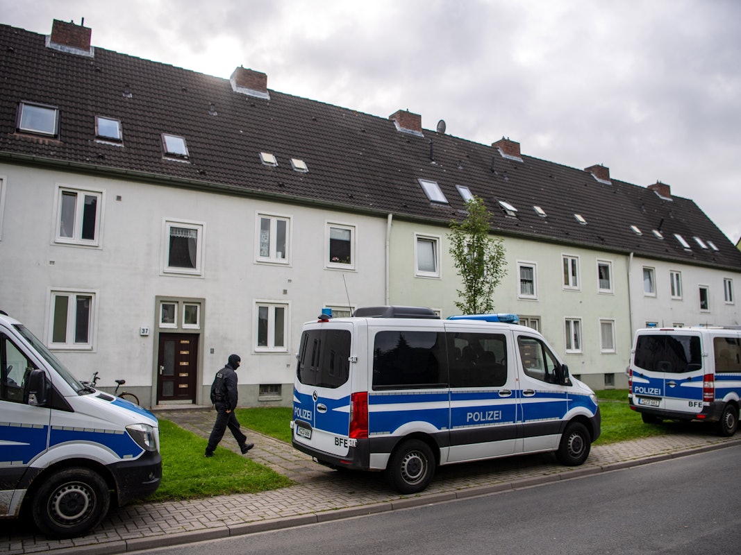 Polizei-Autos vor Wohnhäusern bei einer Razzia. Foto von der dpa, honorarfrei
