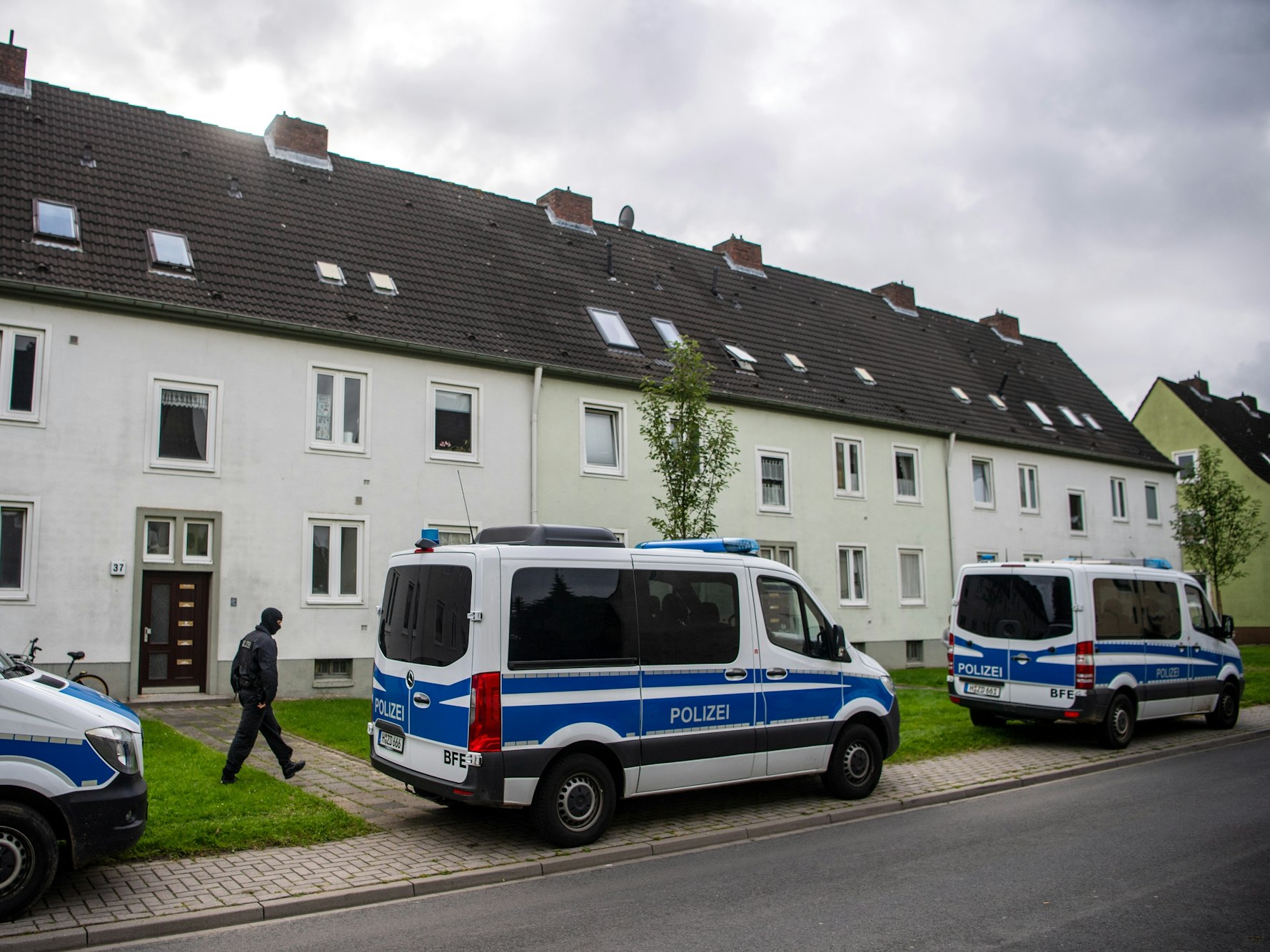 Polizei-Autos vor Wohnhäusern bei einer Razzia. Foto von der dpa, honorarfrei
