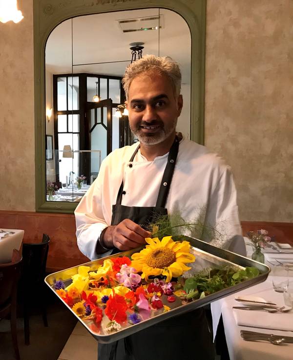 Jaspreet Dhaliwal-Wilmes steht mit einem Tablett Blüten in seinem Restaurant.